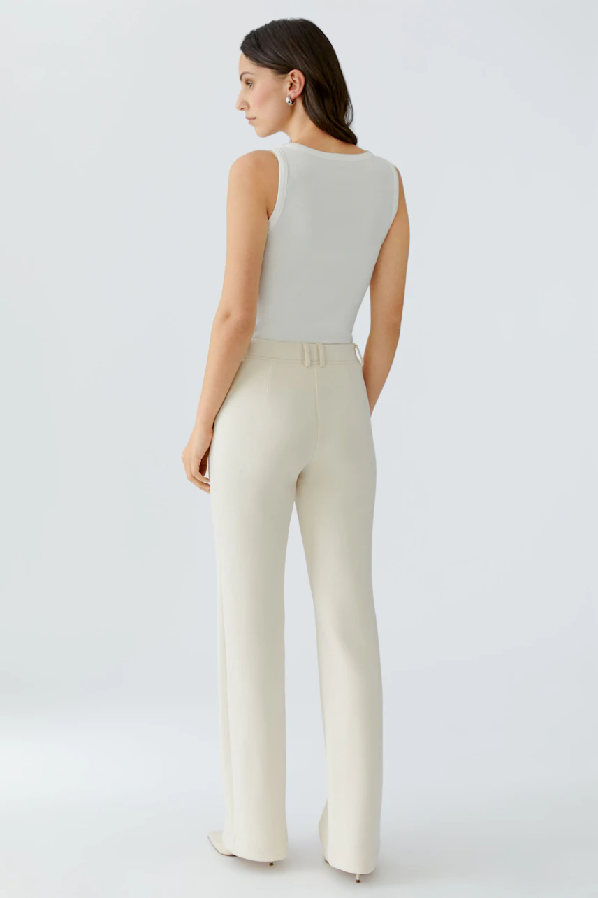 Casual women's trousers: A woman in cream-colored, high-waisted trousers with a fitted silhouette.