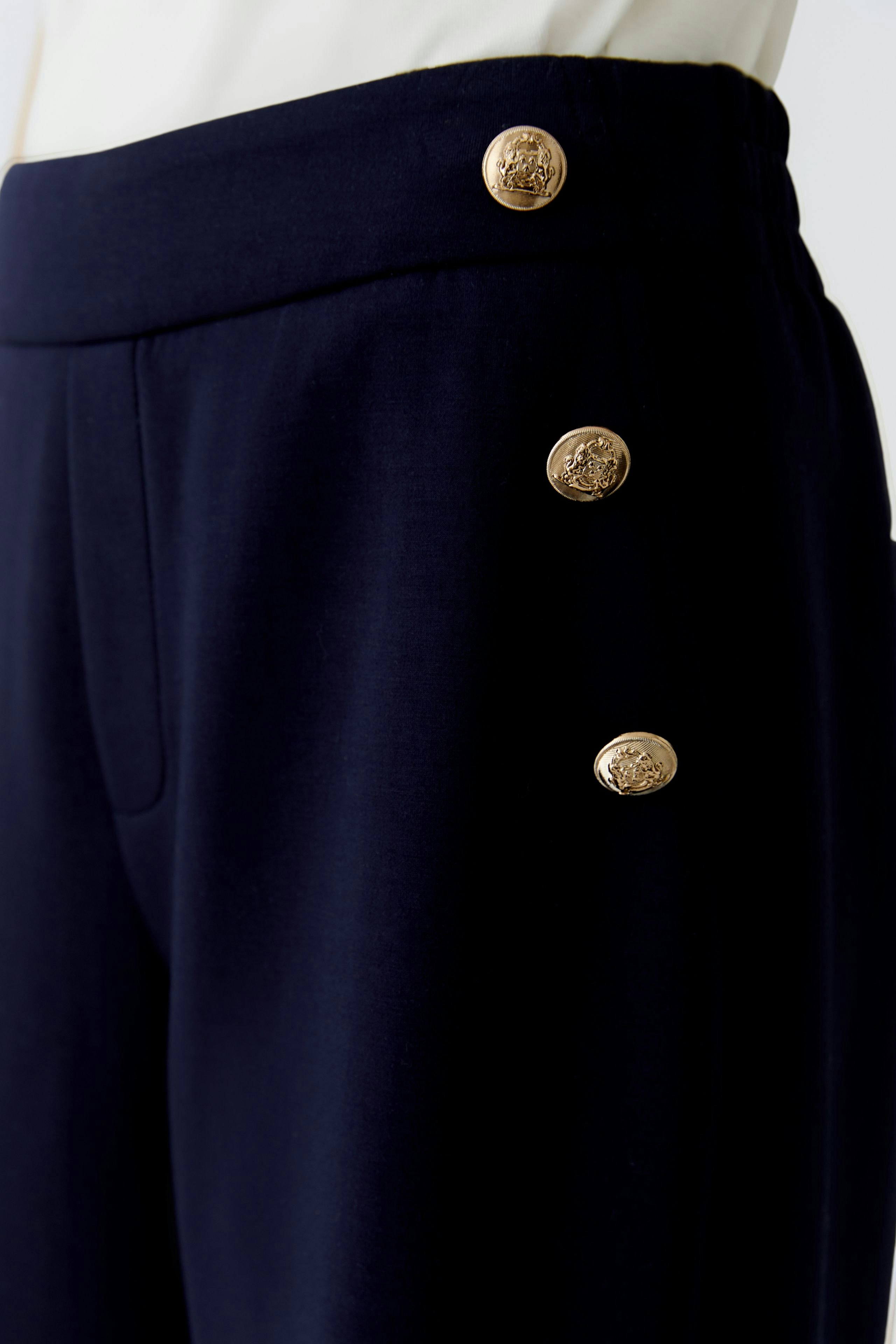 Casual women's trousers: Close-up of navy pants with gold buttons, perfect for everyday wear.