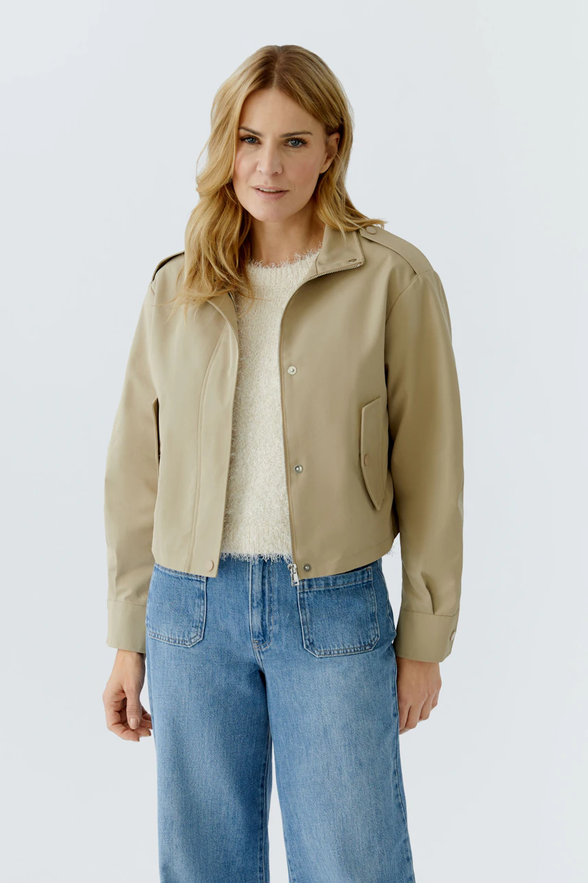 Casual women's blouson: Woman in a beige cropped jacket paired with a cozy pullover and relaxed jeans.