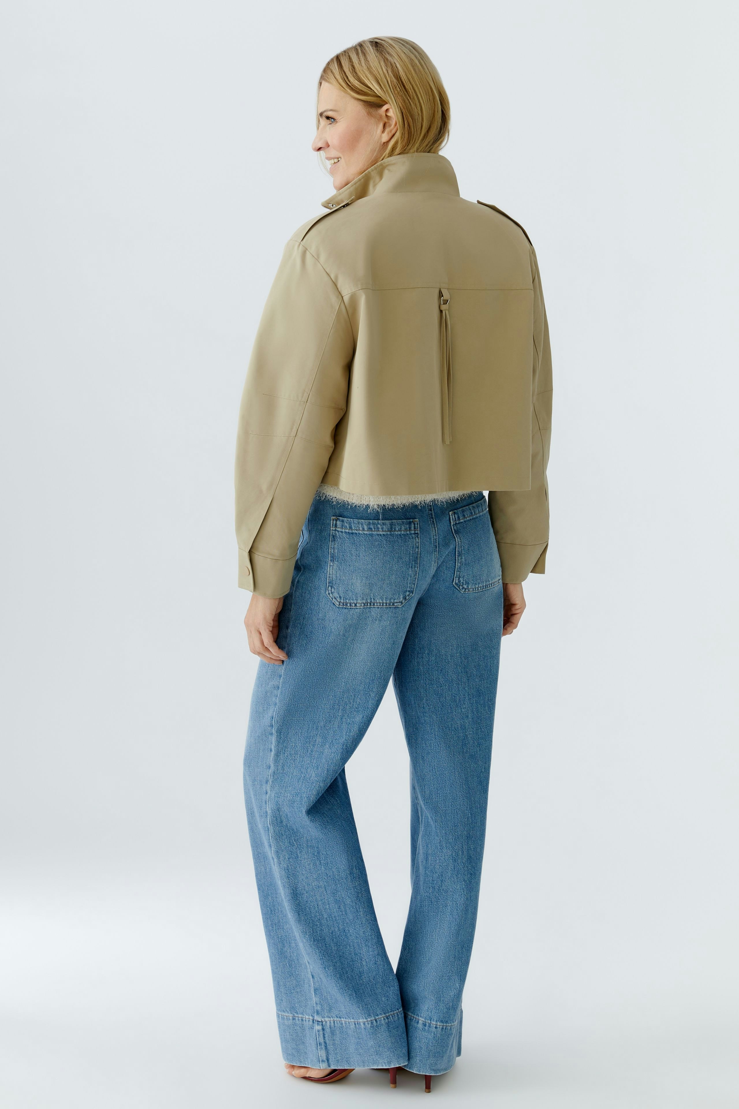 Stylish women's blouson: A woman in a cropped beige jacket paired with wide-leg jeans.