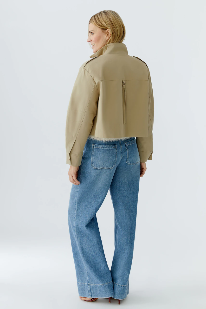 Stylish women's blouson: A woman in a cropped beige jacket paired with wide-leg jeans.