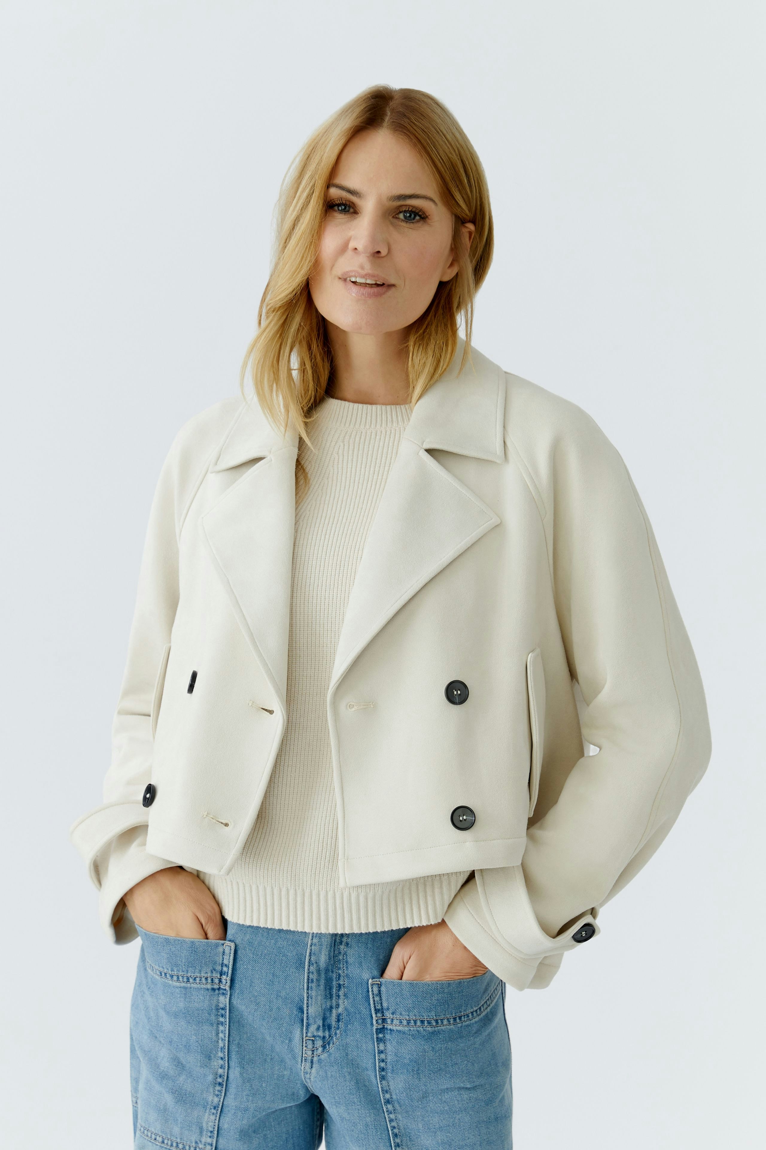 Stylish women's faux leather jacket: A woman in a cream jacket with buttons and a casual pullover.