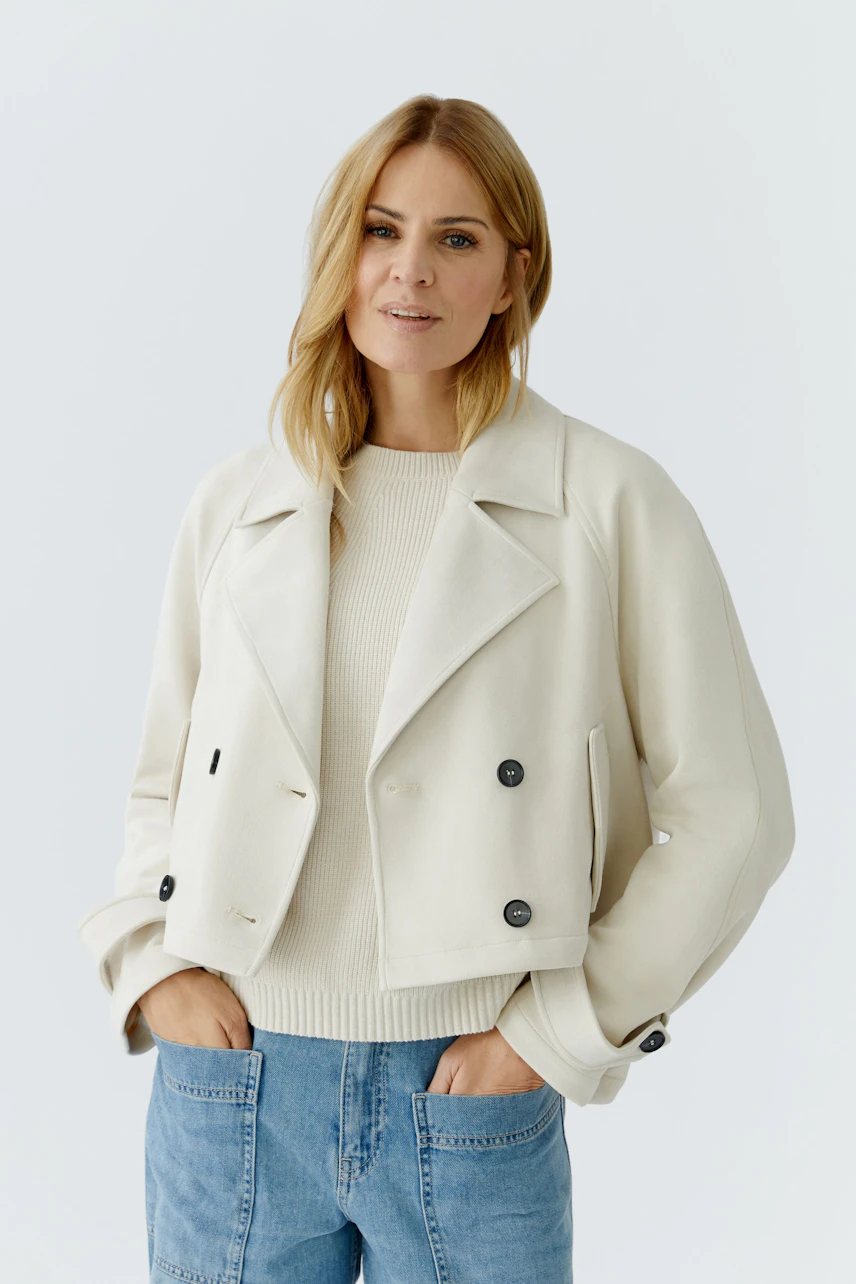 Stylish women's faux leather jacket: A woman in a cream jacket with buttons and a casual pullover.