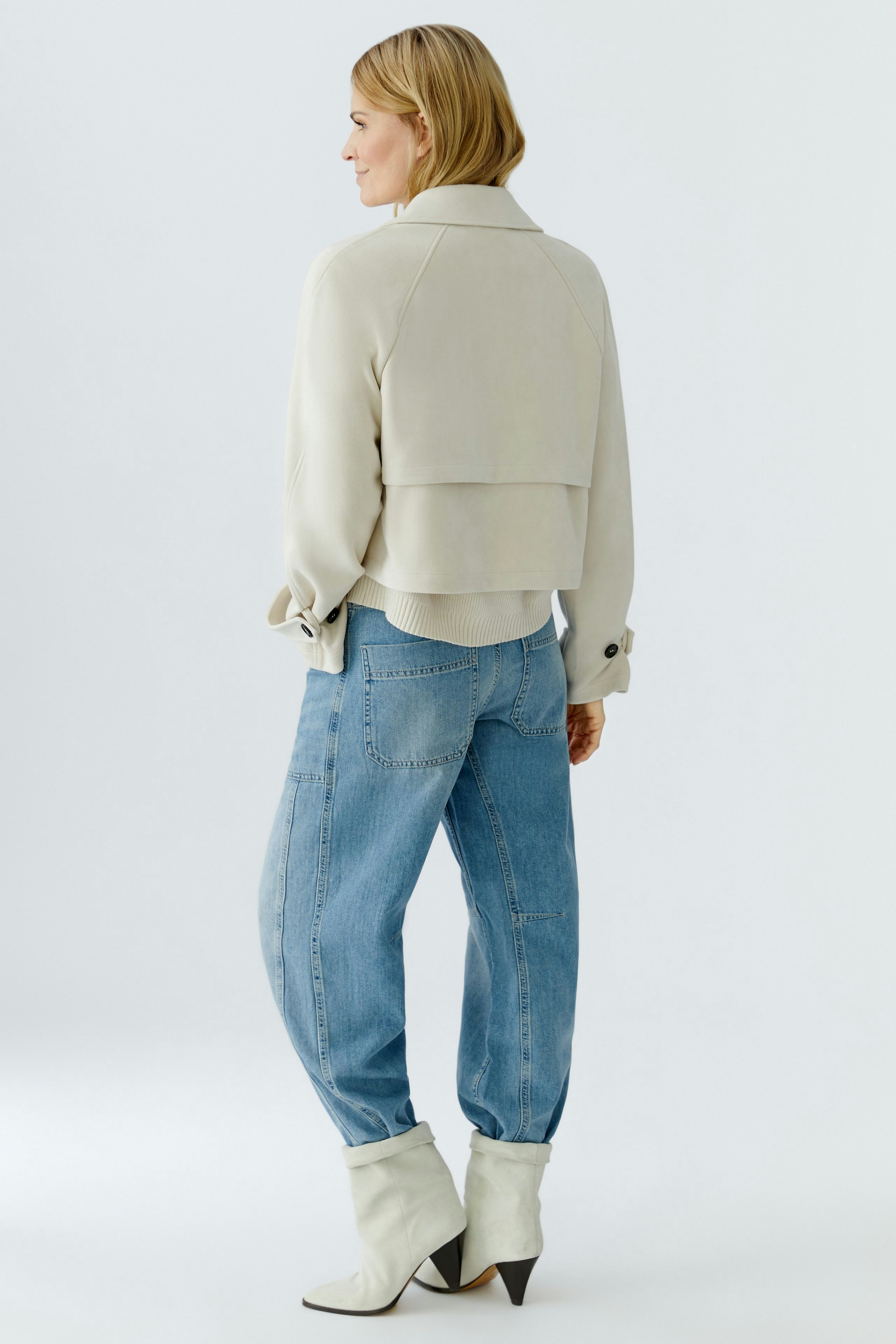 Stylish women's faux leather jacket: A woman in a light jacket paired with relaxed jeans.