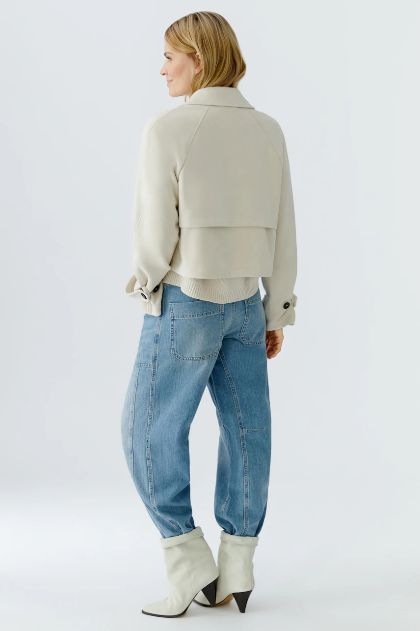 Stylish women's faux leather jacket: A woman in a light jacket paired with relaxed jeans.