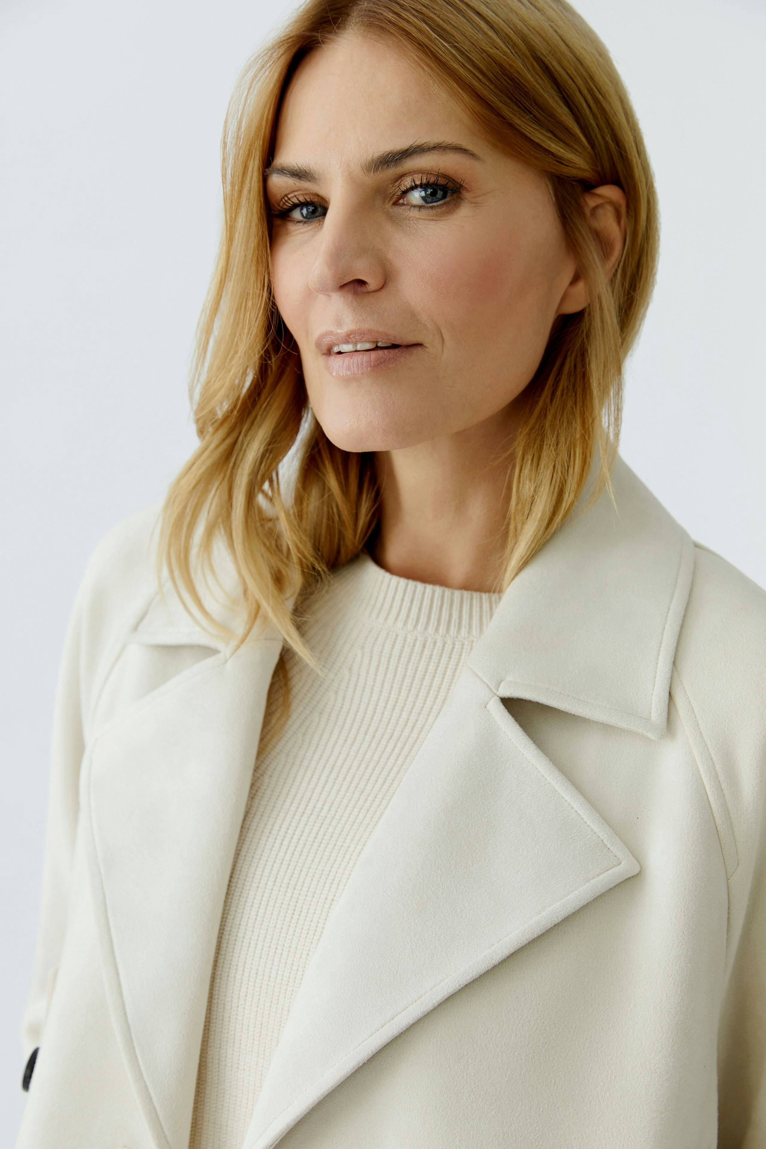 Stylish women's faux leather jacket: A woman in a cream jacket with a classic collar and a relaxed look.