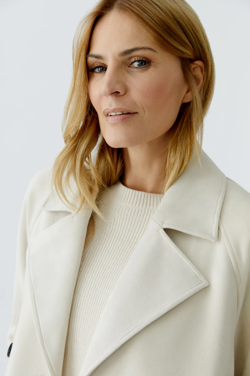 Stylish women's faux leather jacket: A woman in a cream jacket with a classic collar and a relaxed look.