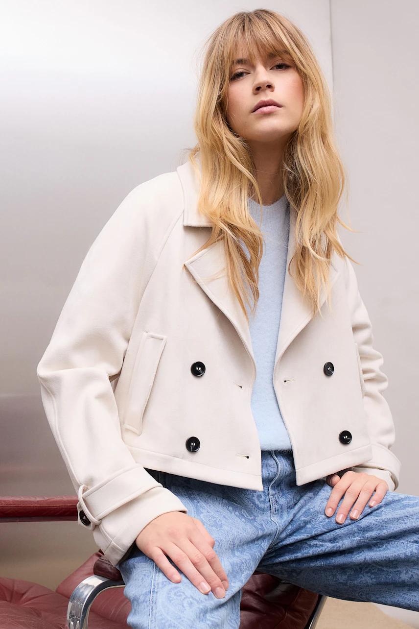 Stylish women's faux leather jacket: A woman in a light jacket with a relaxed fit and button details.