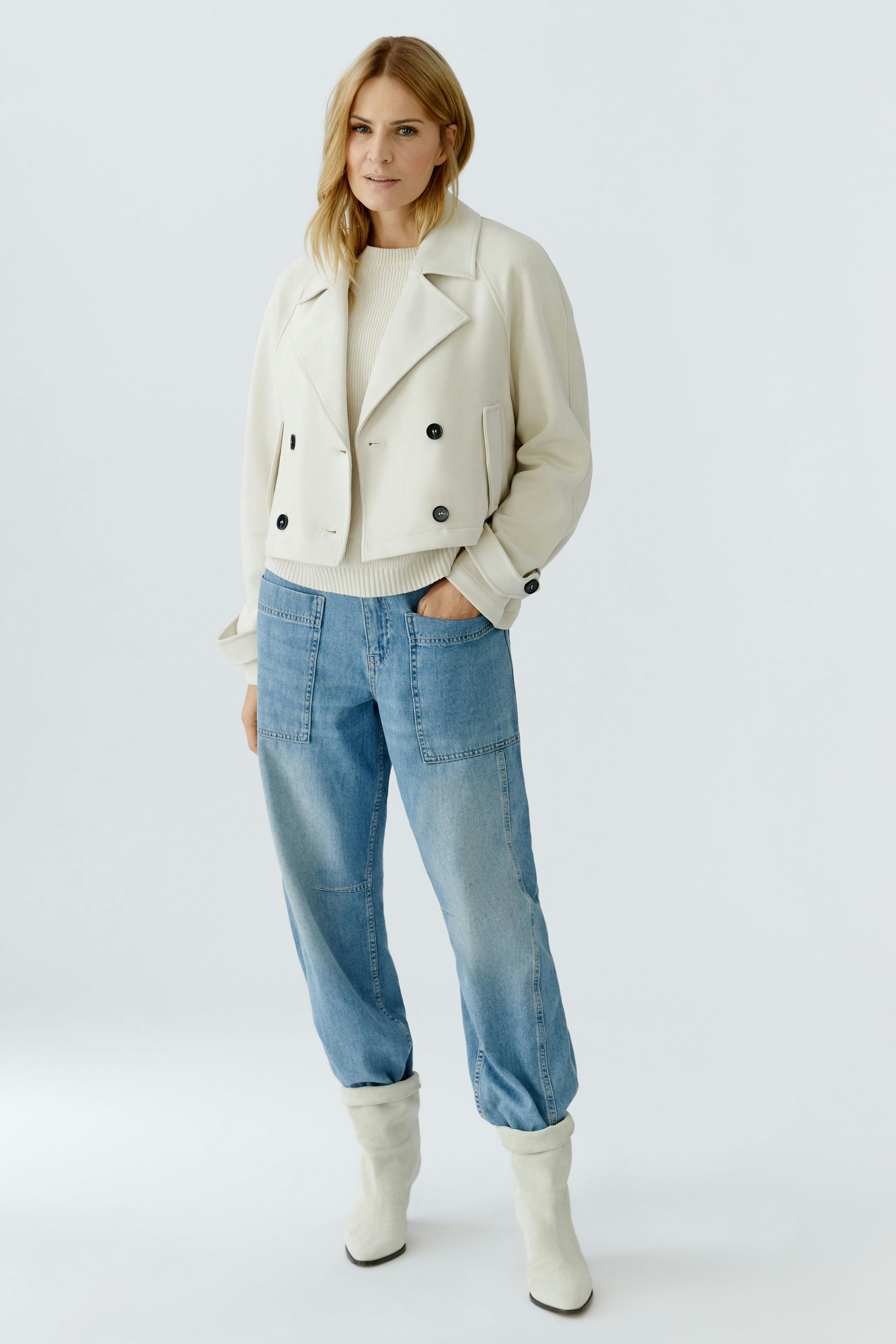 Stylish women's faux leather jacket: A woman in a cream jacket paired with relaxed denim pants.