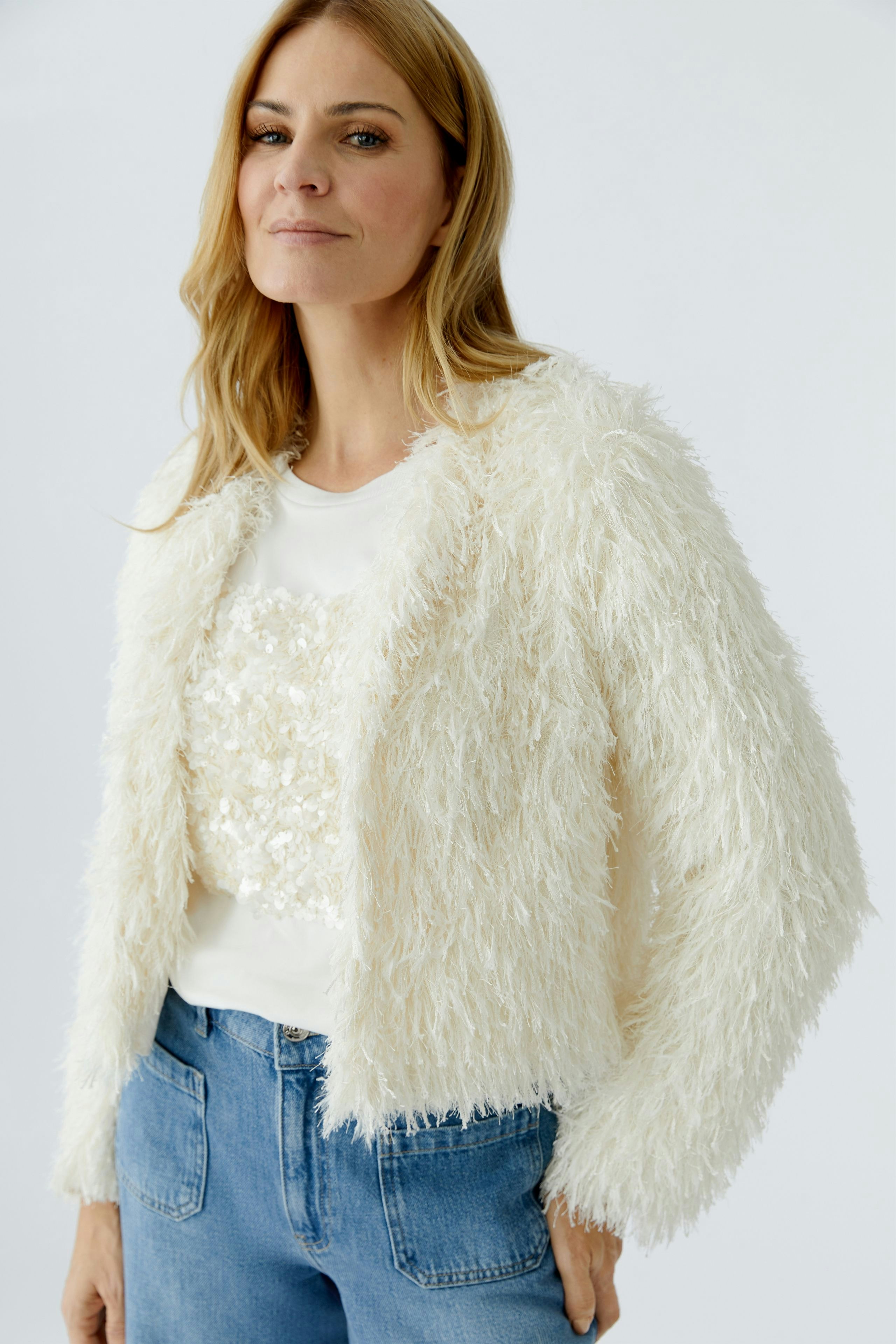Flauschige Damen-Jacke: Frau in weißer, strukturierter Jacke mit lässigem Shirt und Jeans.