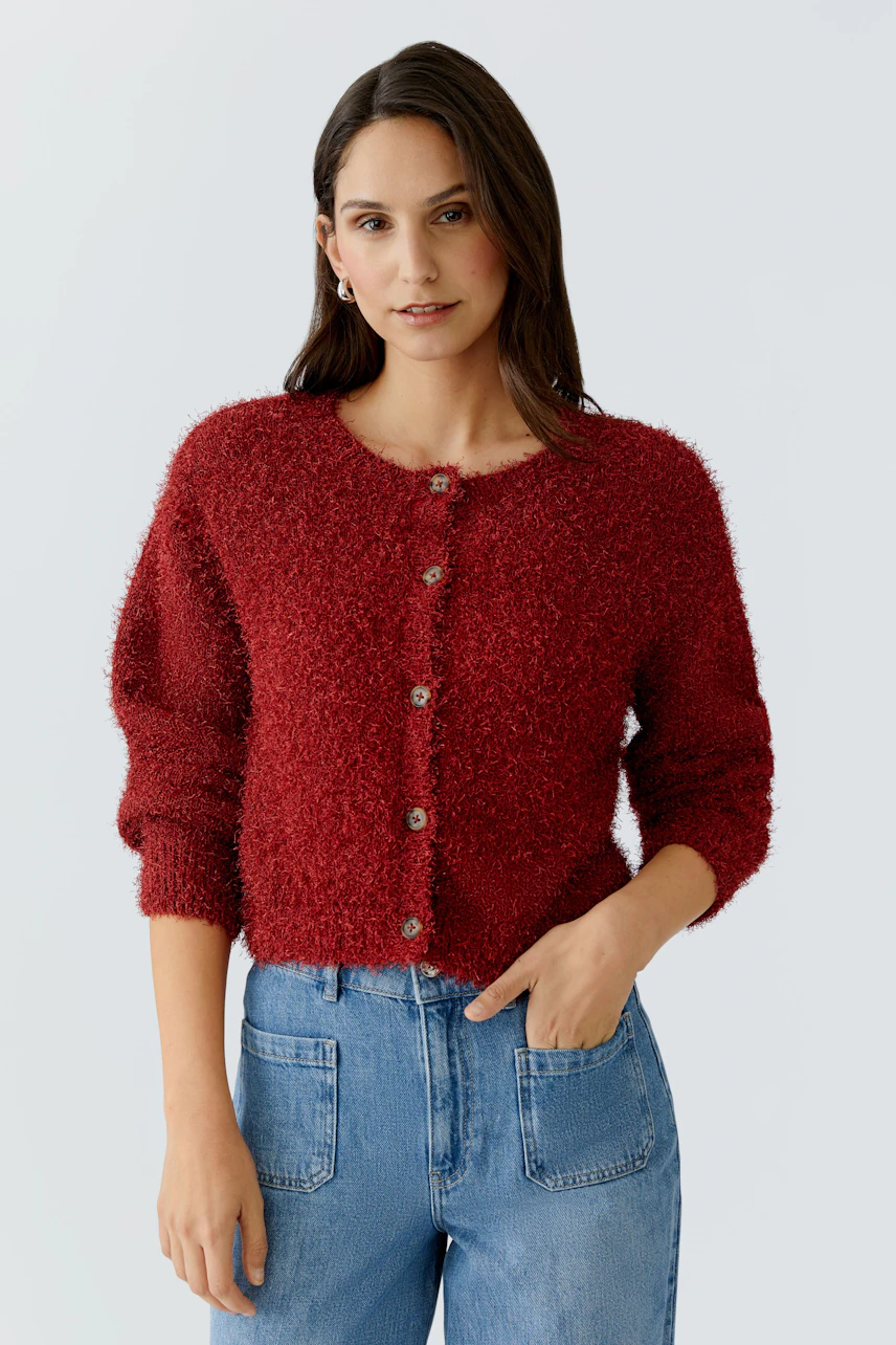Casual women's cardigan: A woman in a cozy red cardigan with buttons and relaxed jeans.