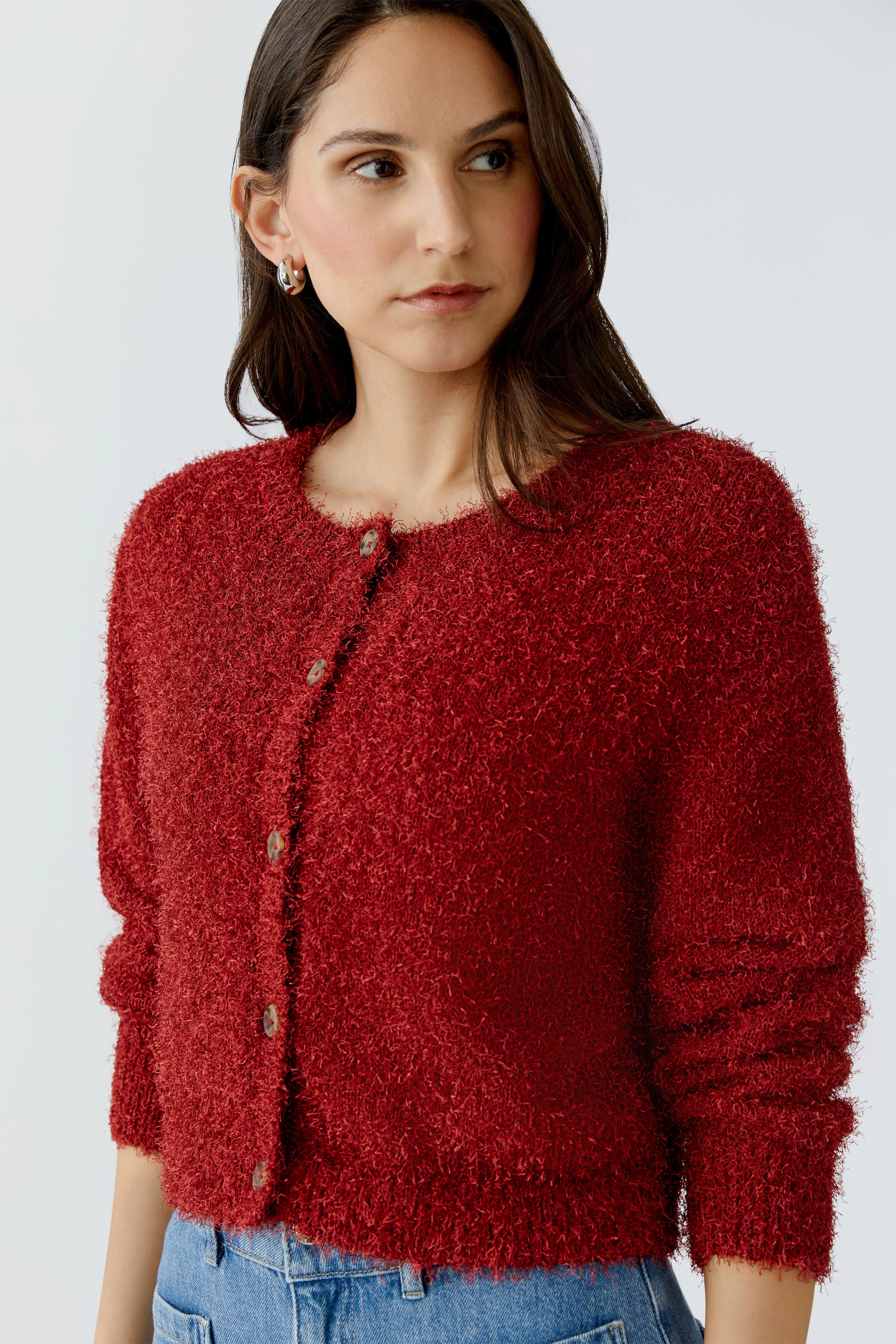 Rote Damen-Strickjacke: Frau trägt eine kuschelige, knopflose Strickjacke in einem warmen Rotton.