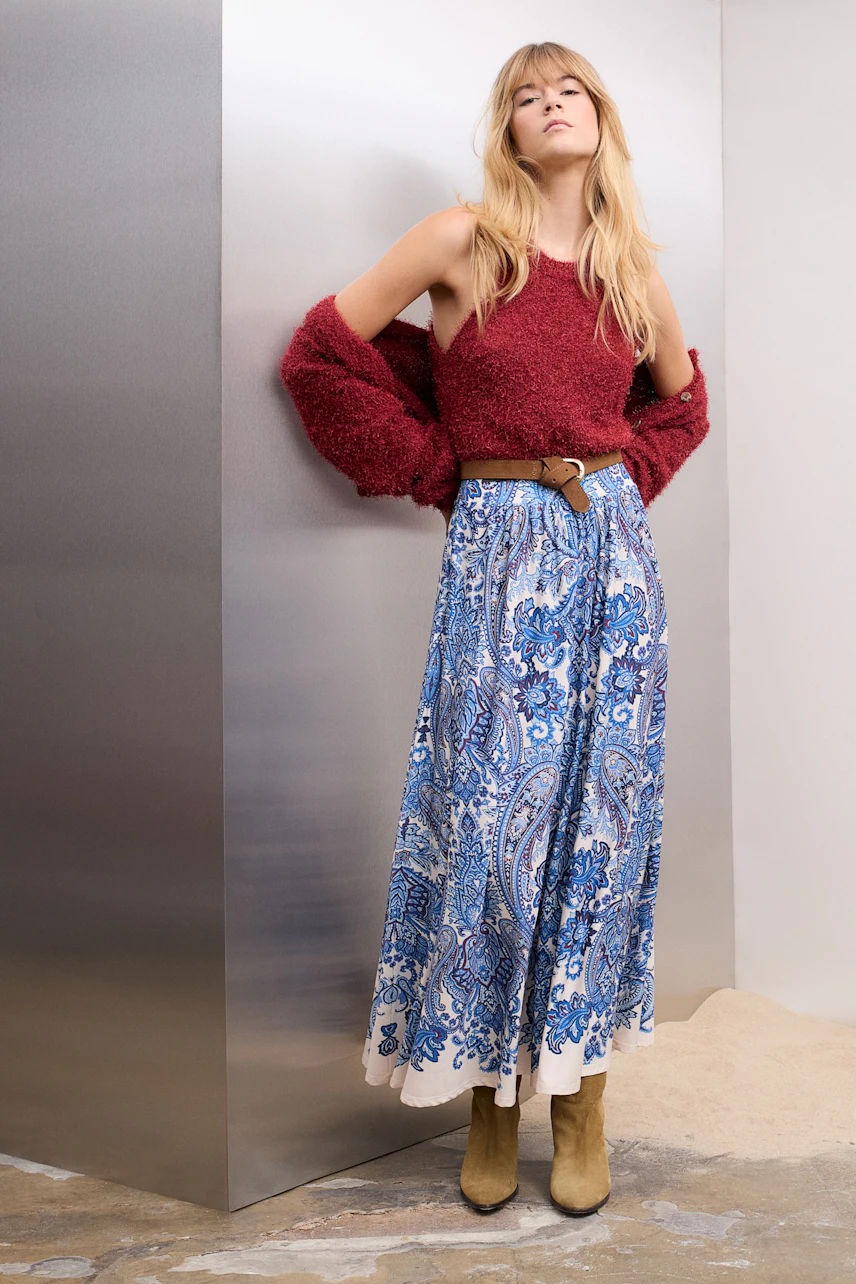 Casual women's cardigan: A woman in a cozy red cardigan paired with a blue patterned skirt.