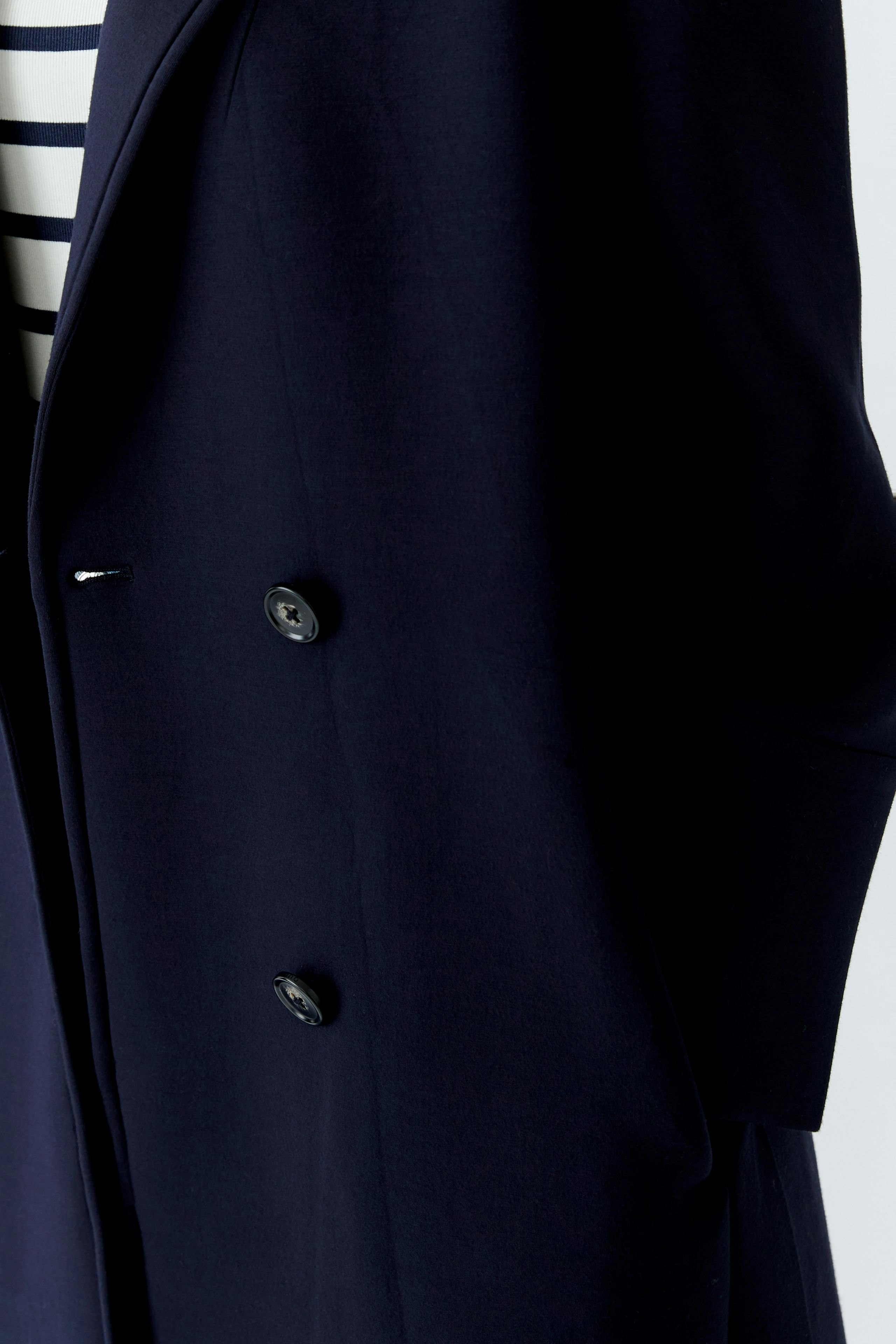 Stylish women's coat: Close-up of a navy coat with buttons, perfect for layering over casual outfits.