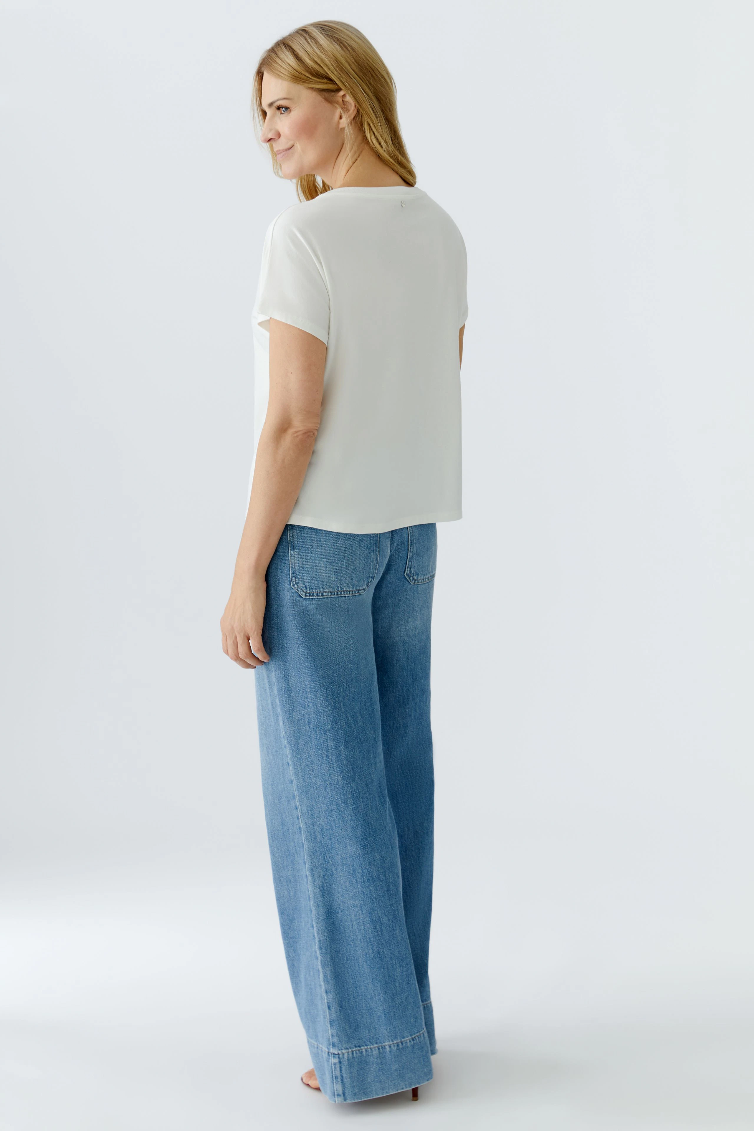 Damen-T-Shirt: Frau in einem weißen, lässigen T-Shirt mit kurzen Ärmeln und lockeren Jeans.