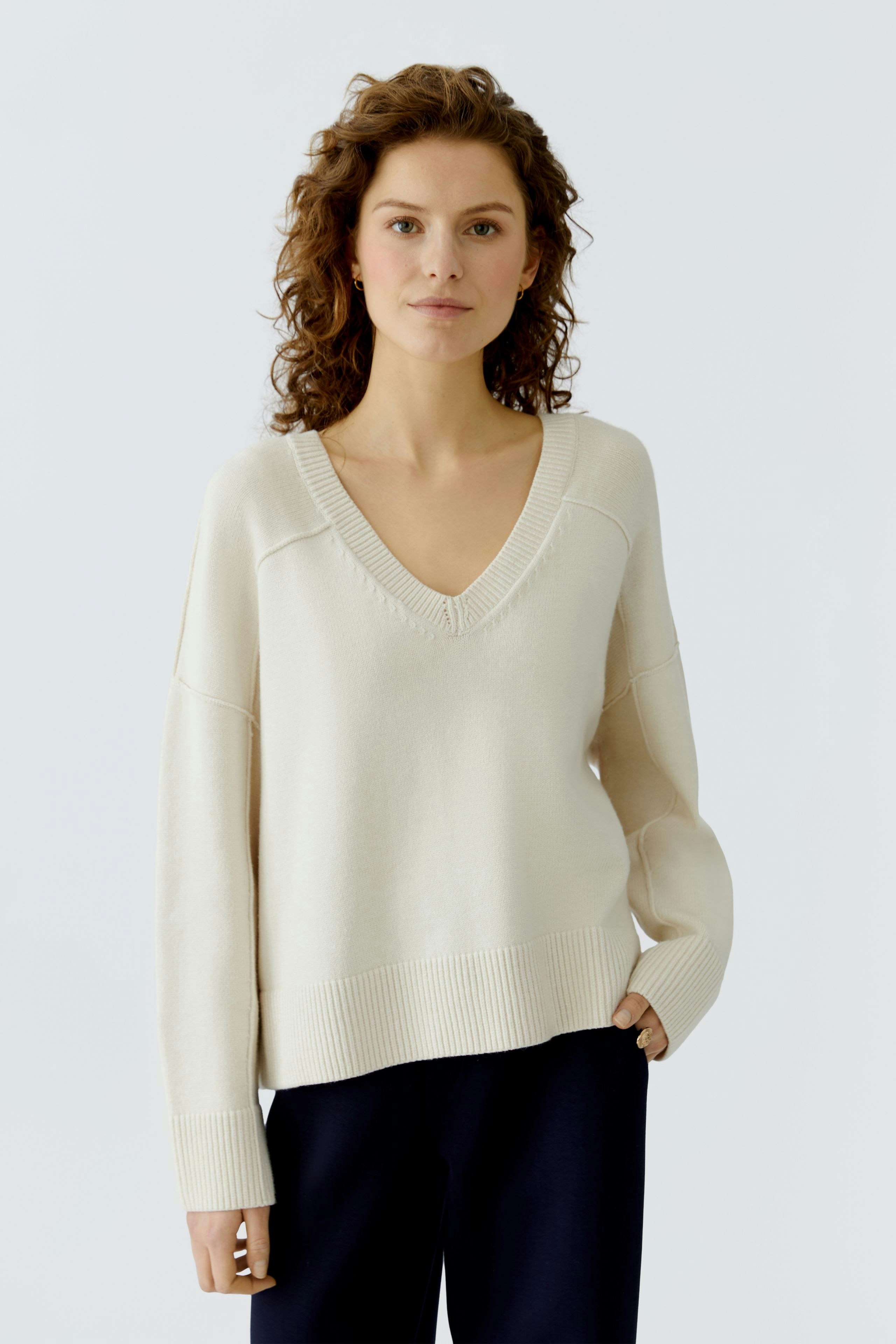 Casual women's pullover: A woman in a light beige pullover with a V-neck and relaxed fit.