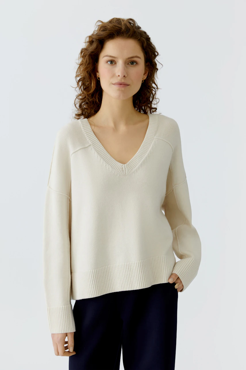 Casual women's pullover: A woman in a light beige pullover with a V-neck and relaxed fit.