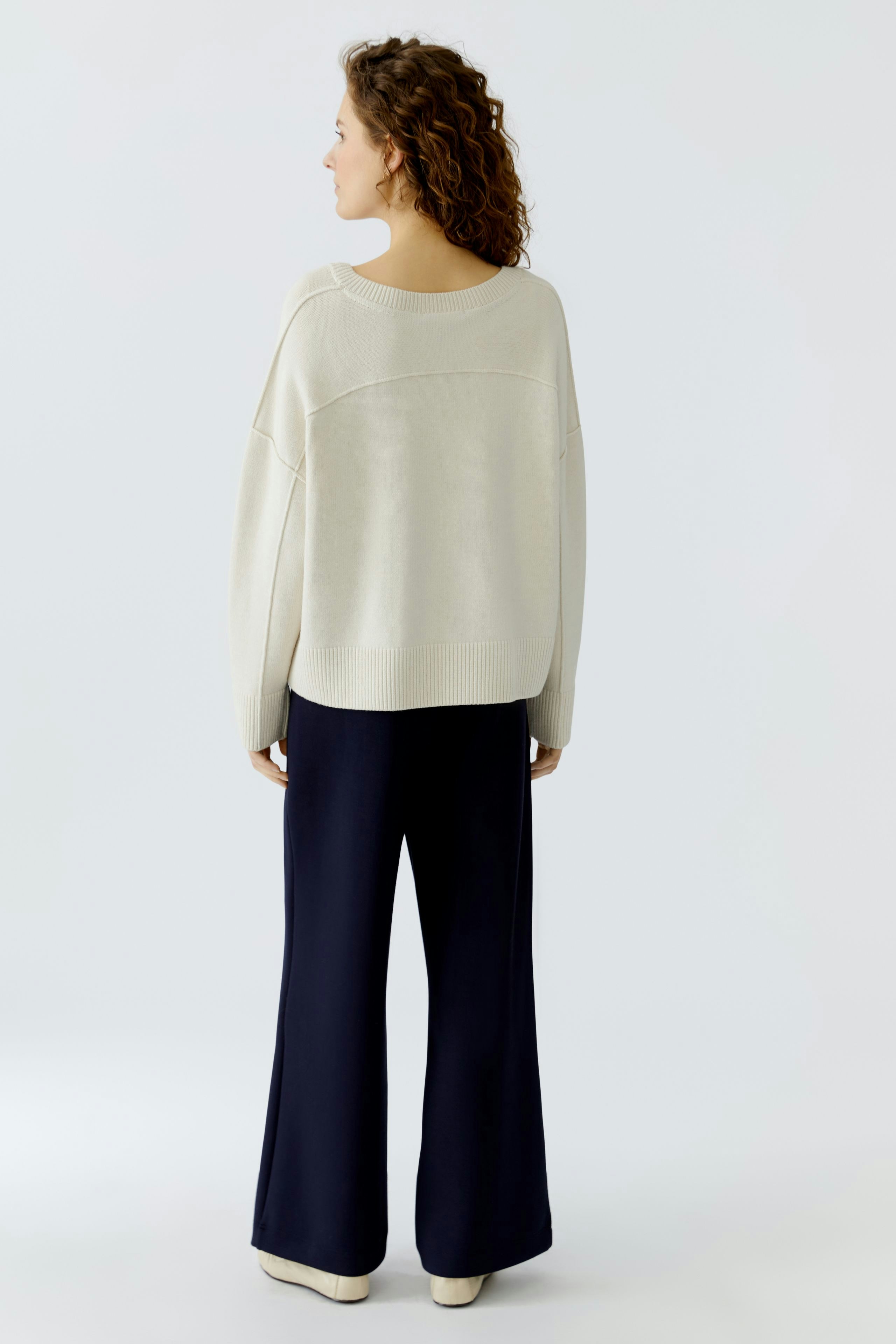 Casual women's pullover: A woman in a light beige pullover with a relaxed fit, paired with navy pants.