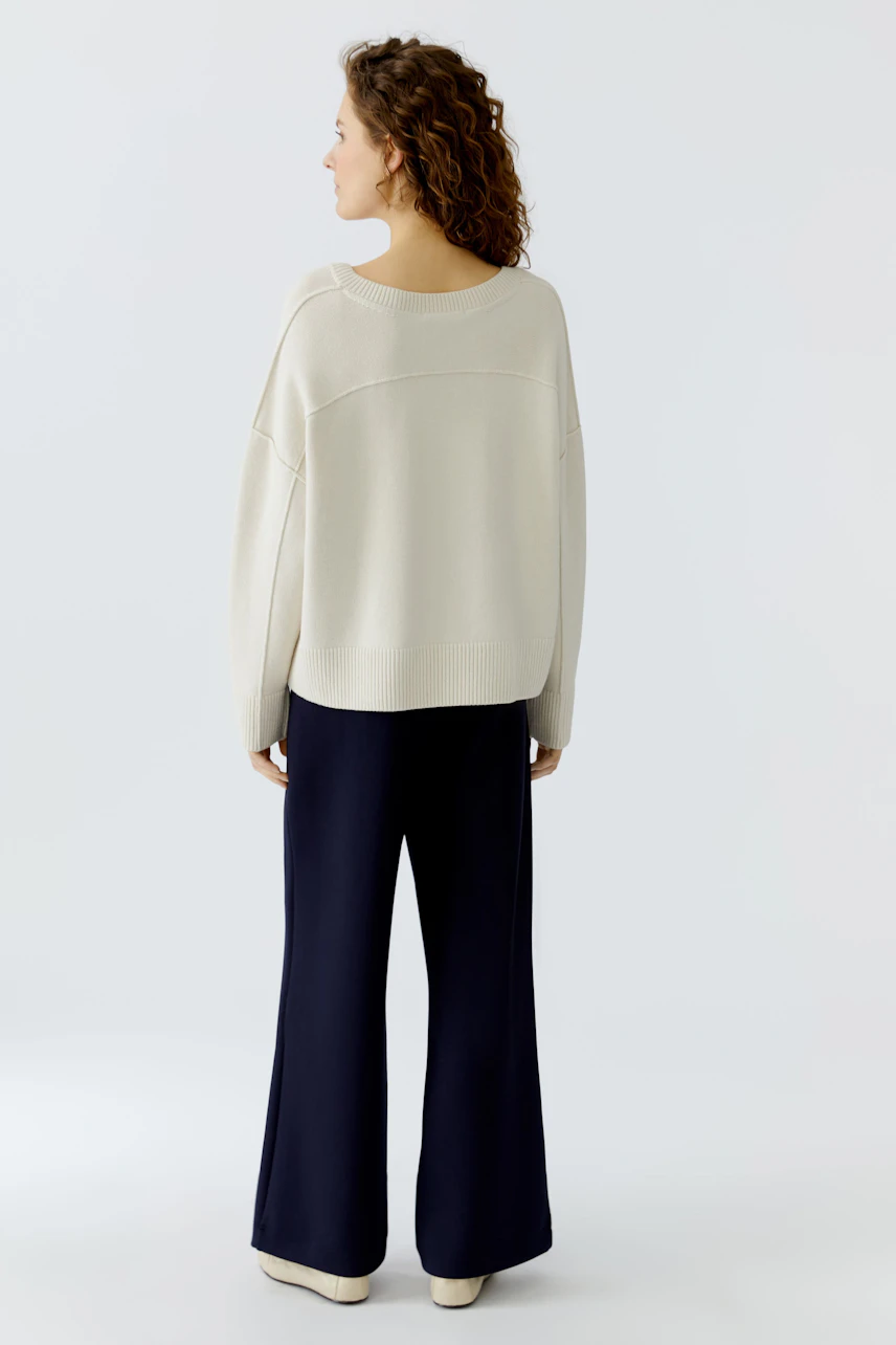 Casual women's pullover: A woman in a light beige pullover with a relaxed fit, paired with navy pants.