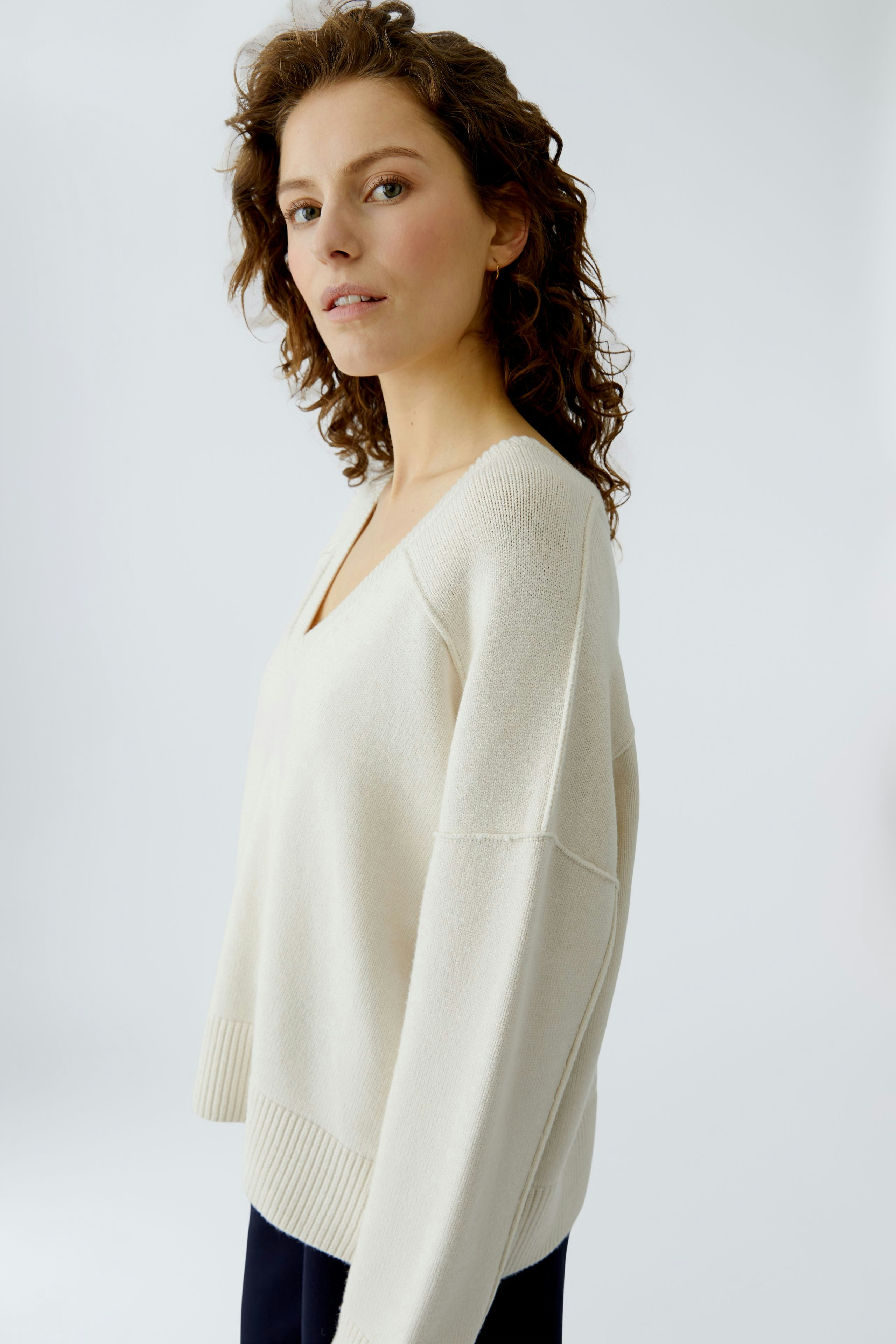 Casual women's pullover: A woman in a light beige pullover with a V-neck and relaxed fit.