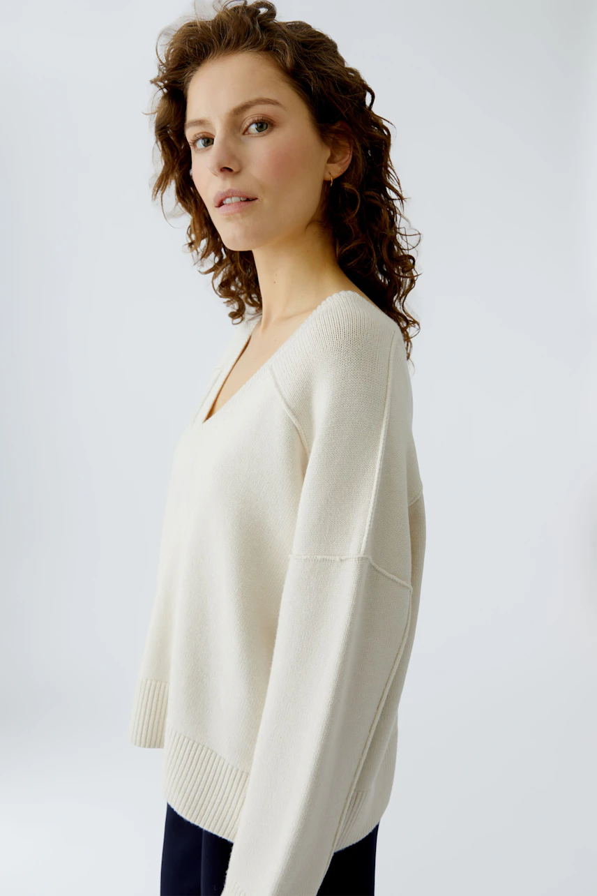 Casual women's pullover: A woman in a light beige pullover with a V-neck and relaxed fit.