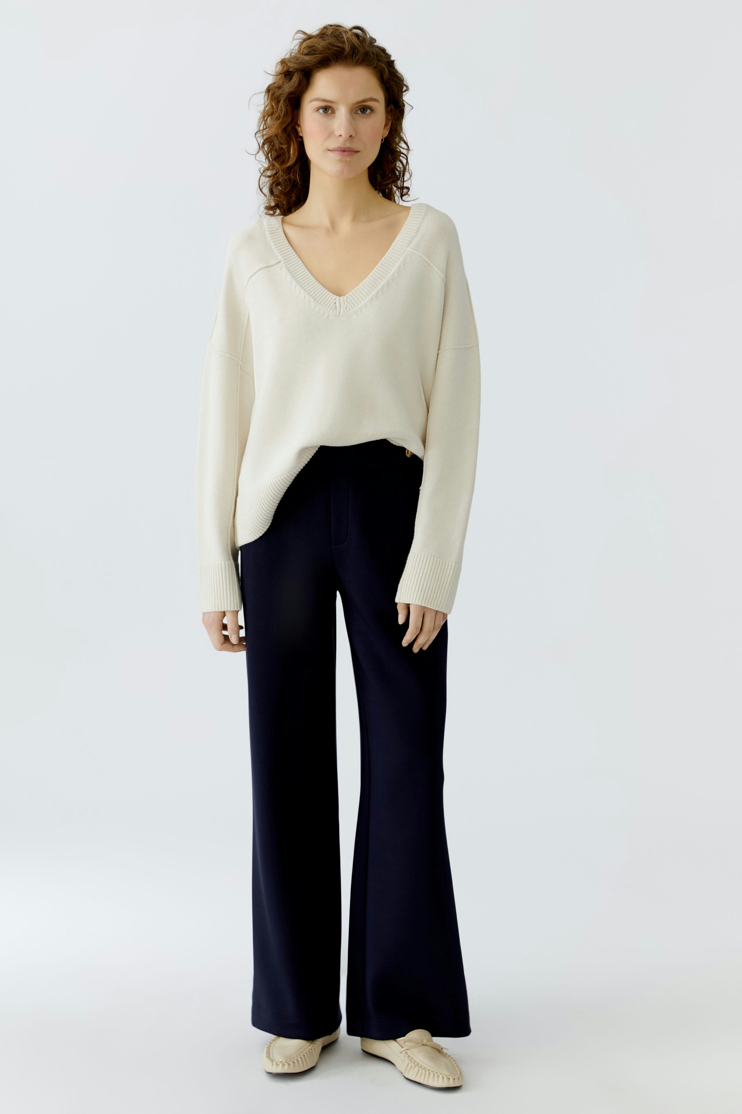 Casual women's pullover: A woman in a cream V-neck pullover paired with wide-leg pants.