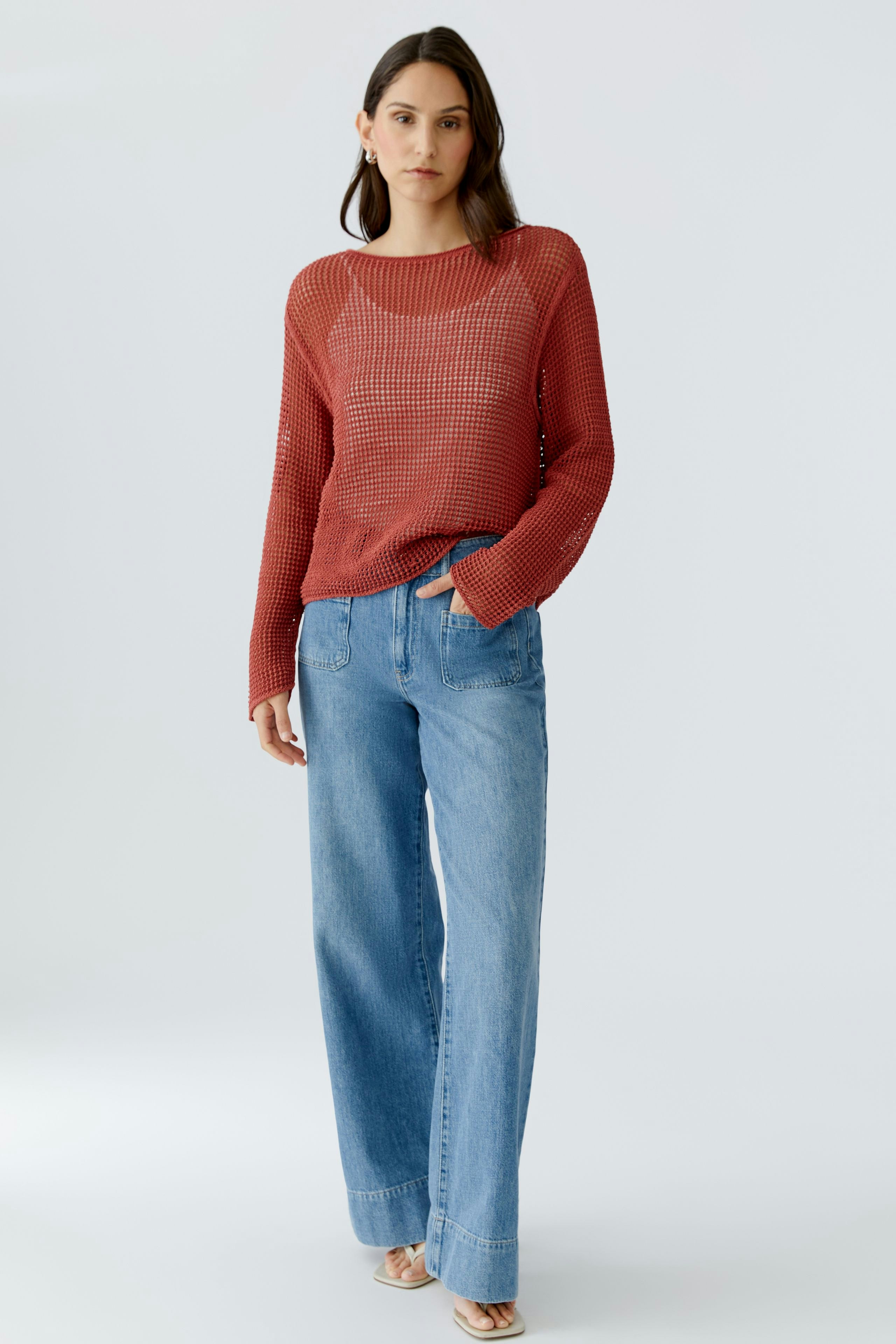 Casual women's pullover: A woman in a red knit pullover paired with wide-leg jeans.