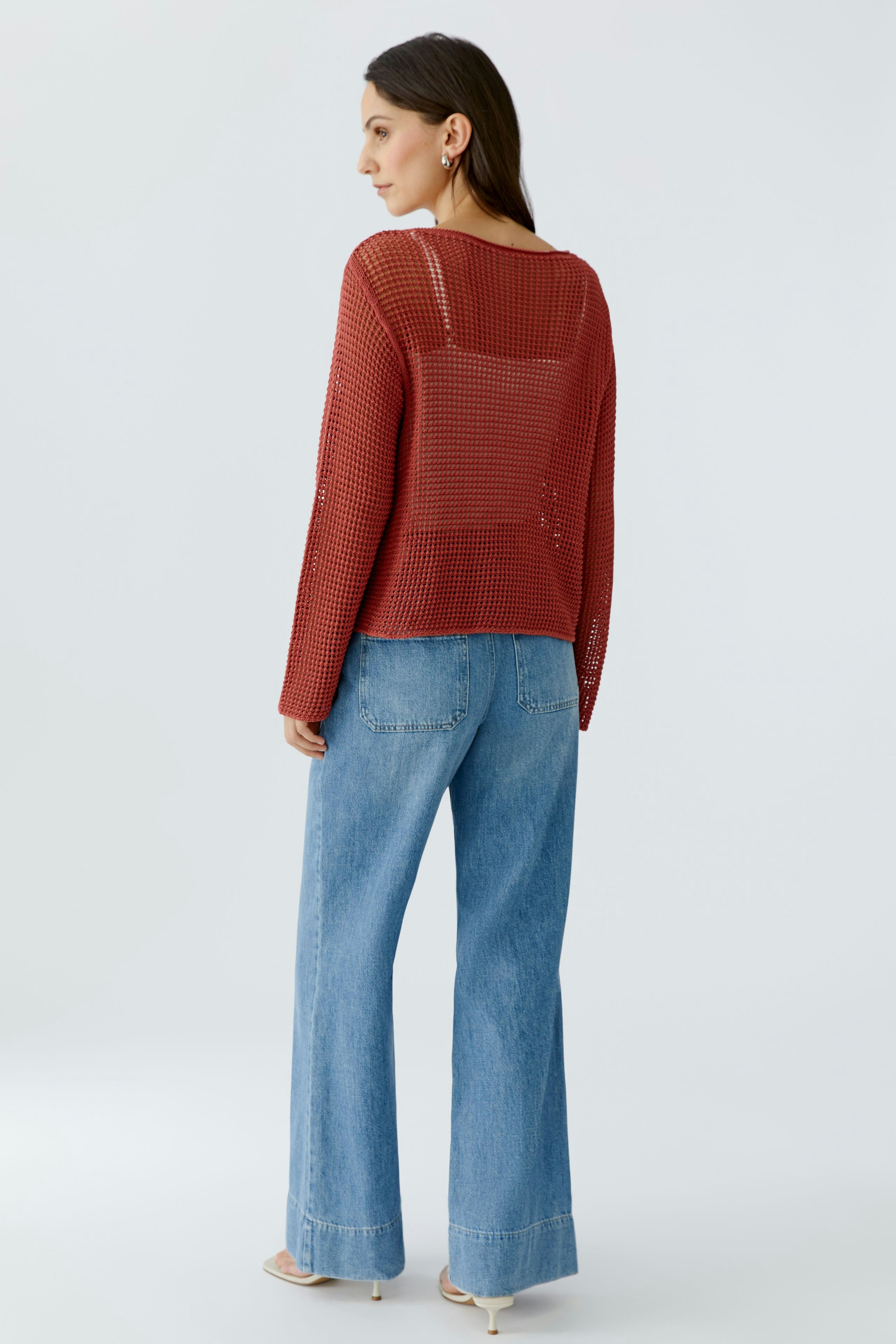 Casual women's pullover: A woman in a loose red knit pullover paired with wide-leg jeans.