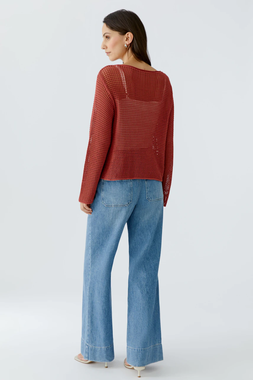Casual women's pullover: A woman in a loose red knit pullover paired with wide-leg jeans.