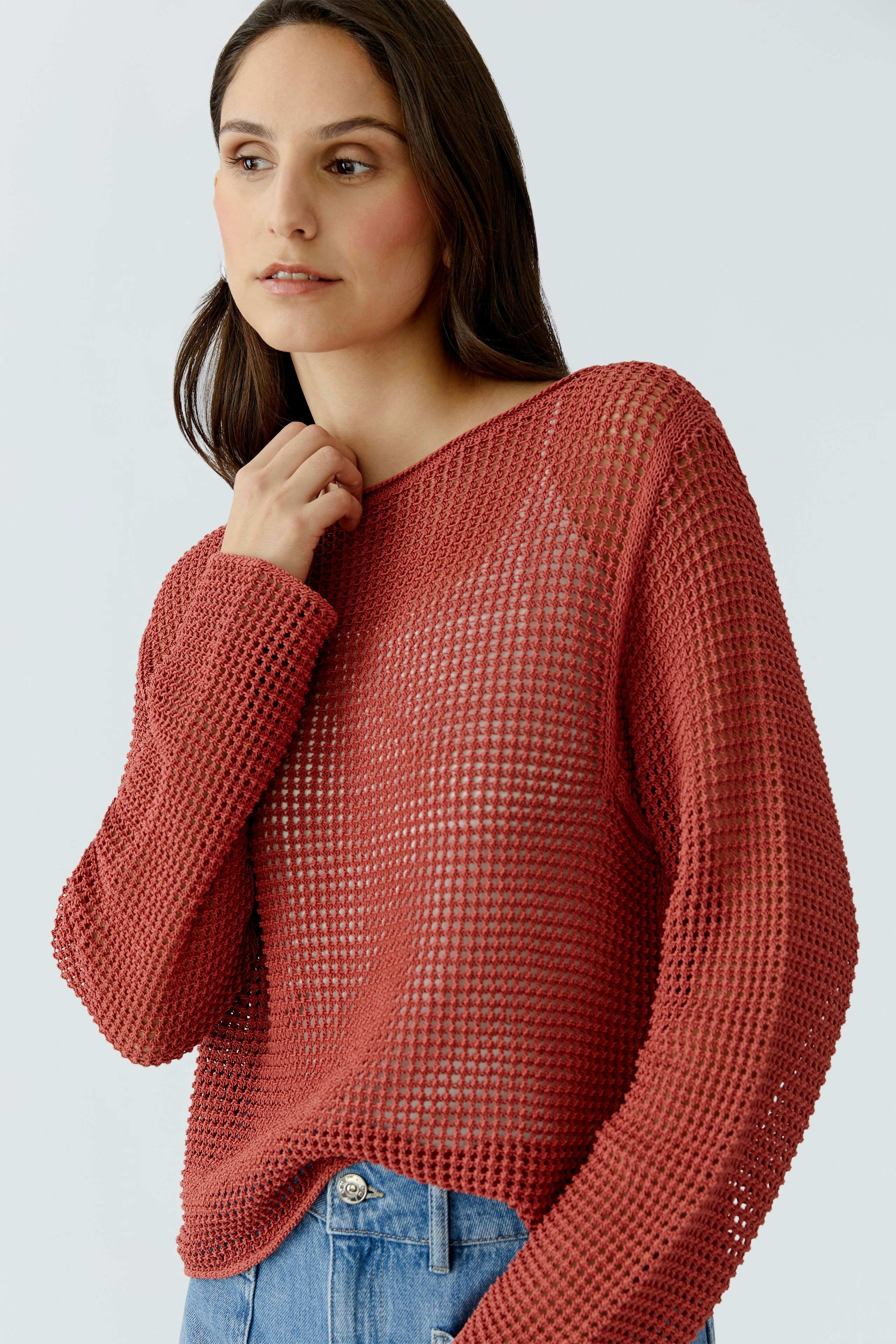 Casual women's pullover: A woman in a loose-knit, rust-colored pullover with a relaxed fit.