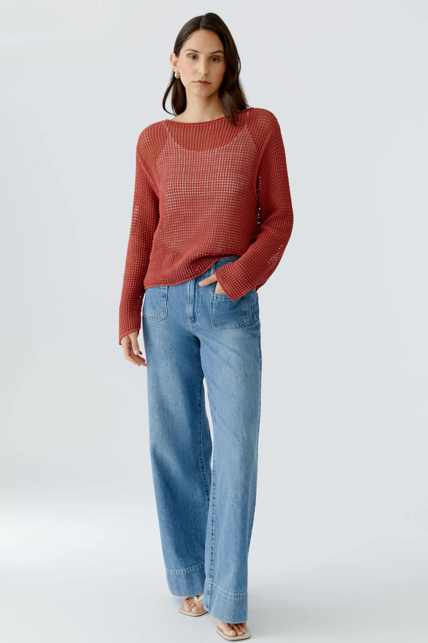 Casual women's pullover: A woman in a red knit pullover paired with wide-leg jeans.