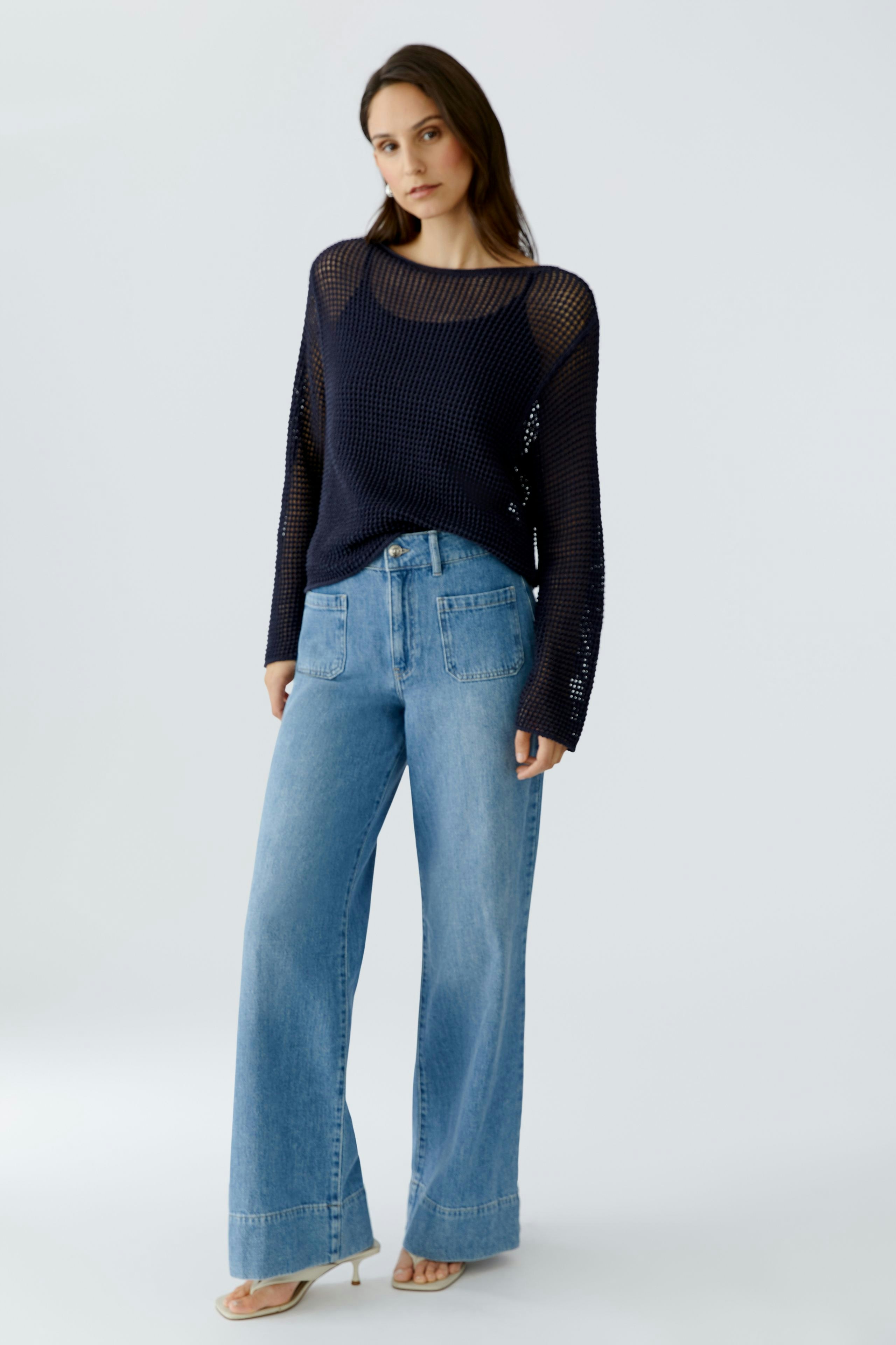 Casual women's pullover: A woman in a navy knit pullover paired with wide-leg jeans stands confidently.
