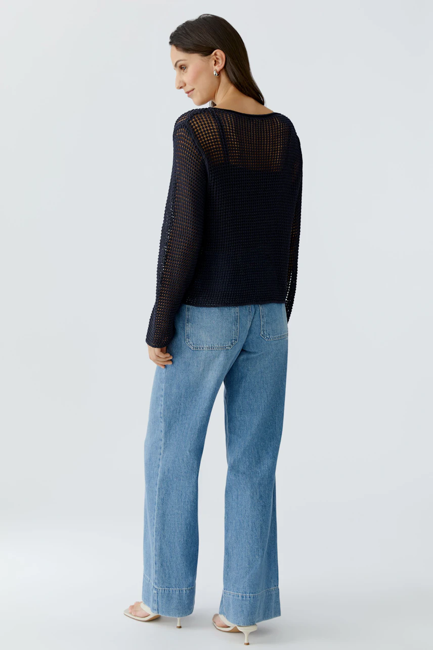 Damen-Pullover: Frau in einem luftigen, dunkelblauen Strickpullover mit lockerer Passform und weiten Jeans.