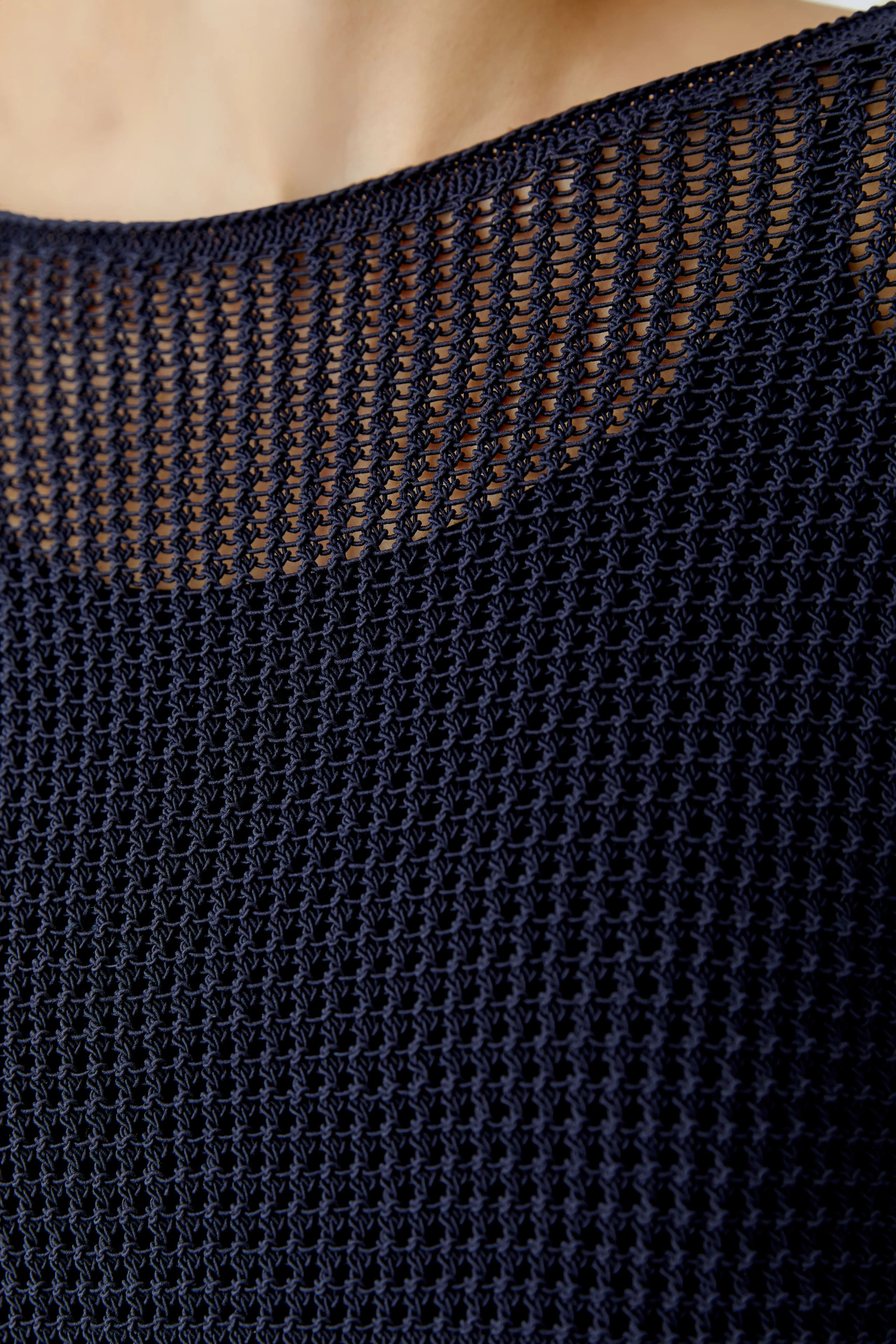Casual women's pullover: Close-up of a woman wearing a navy knitted pullover with a textured design.