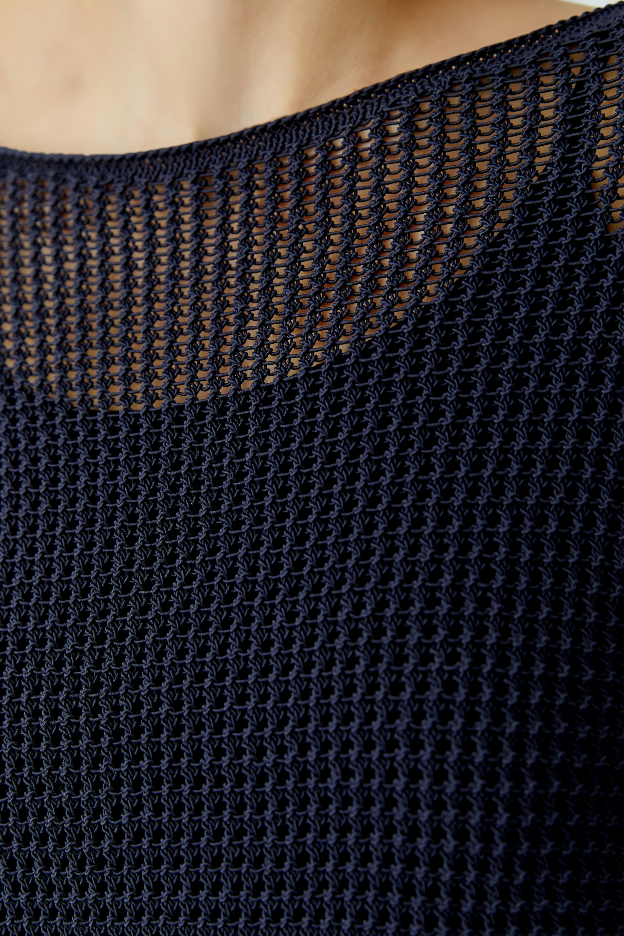 Casual women's pullover: Close-up of a woman wearing a navy knitted pullover with a textured design.