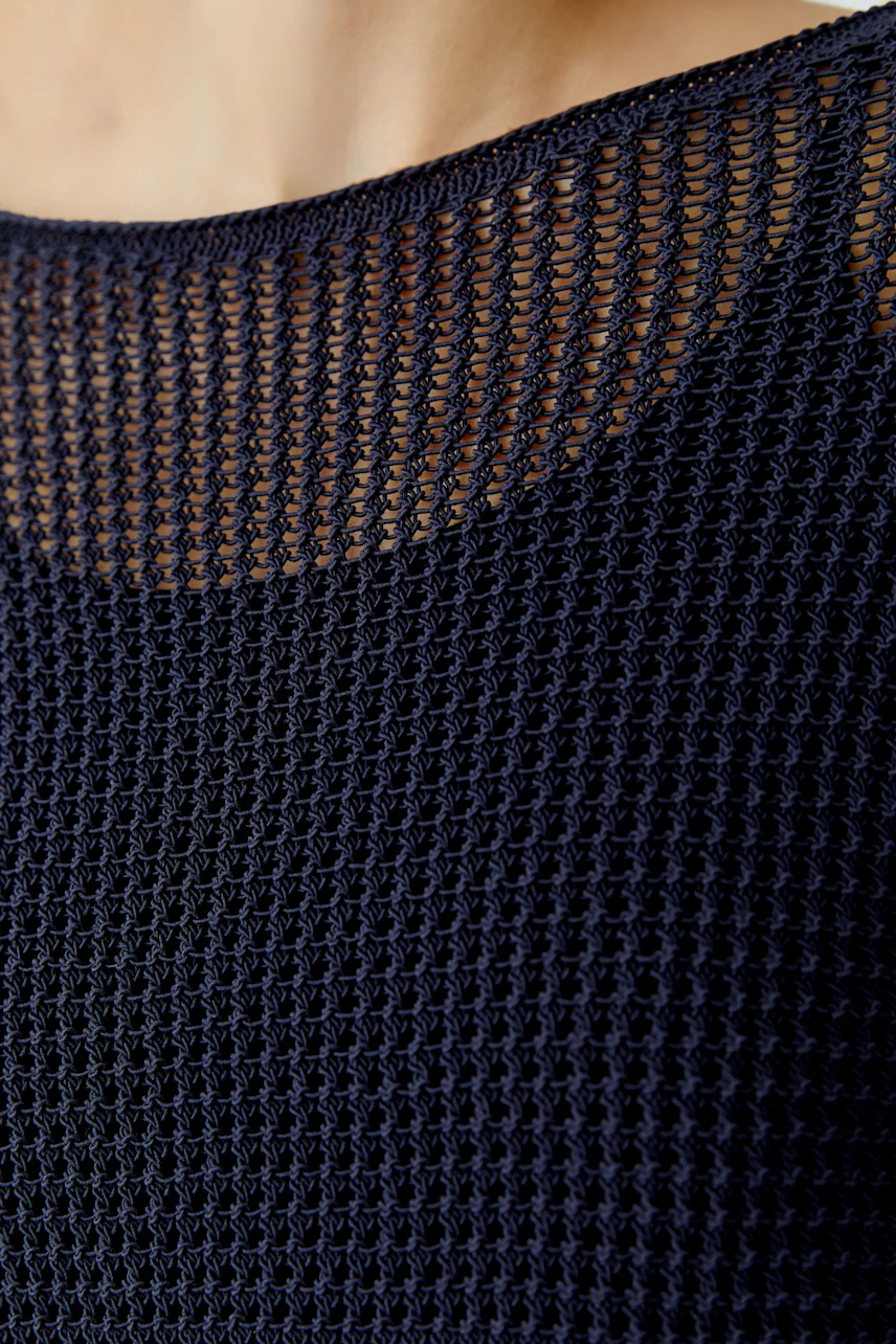 Damen-Pullover: Frau trägt einen luftigen, dunkelblauen Strickpullover mit feiner Netzstruktur.