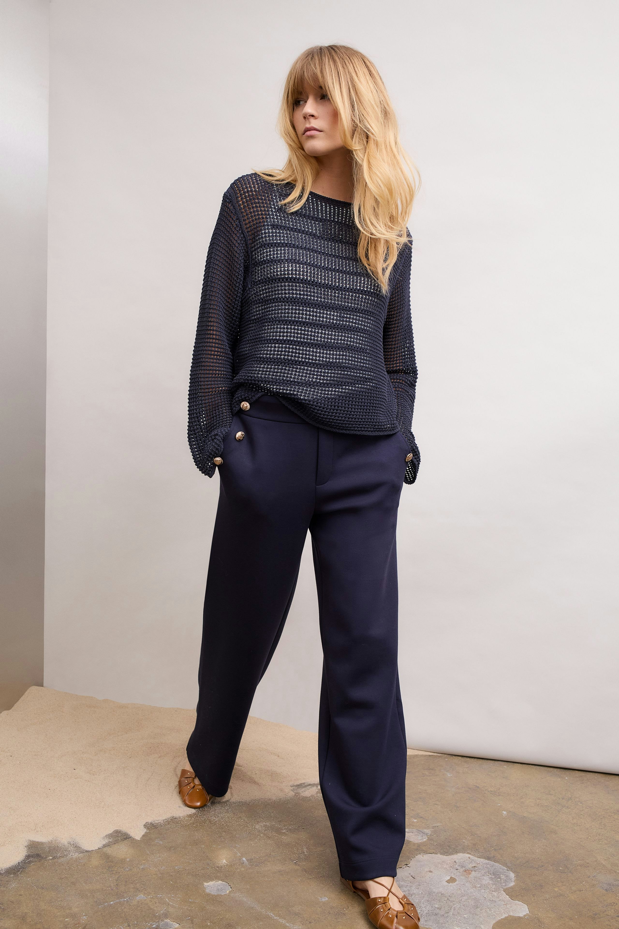 Casual women's pullover: Woman in a navy mesh pullover paired with relaxed-fit trousers.