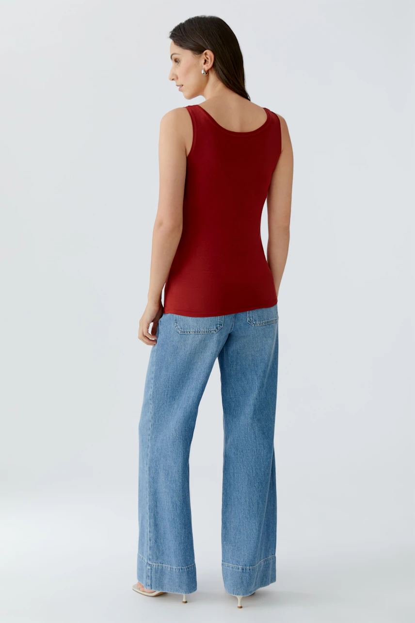 Rotes Damen-Tank Top: Frau trägt ein figurbetontes Top mit breiten Trägern und lässigen Jeans.