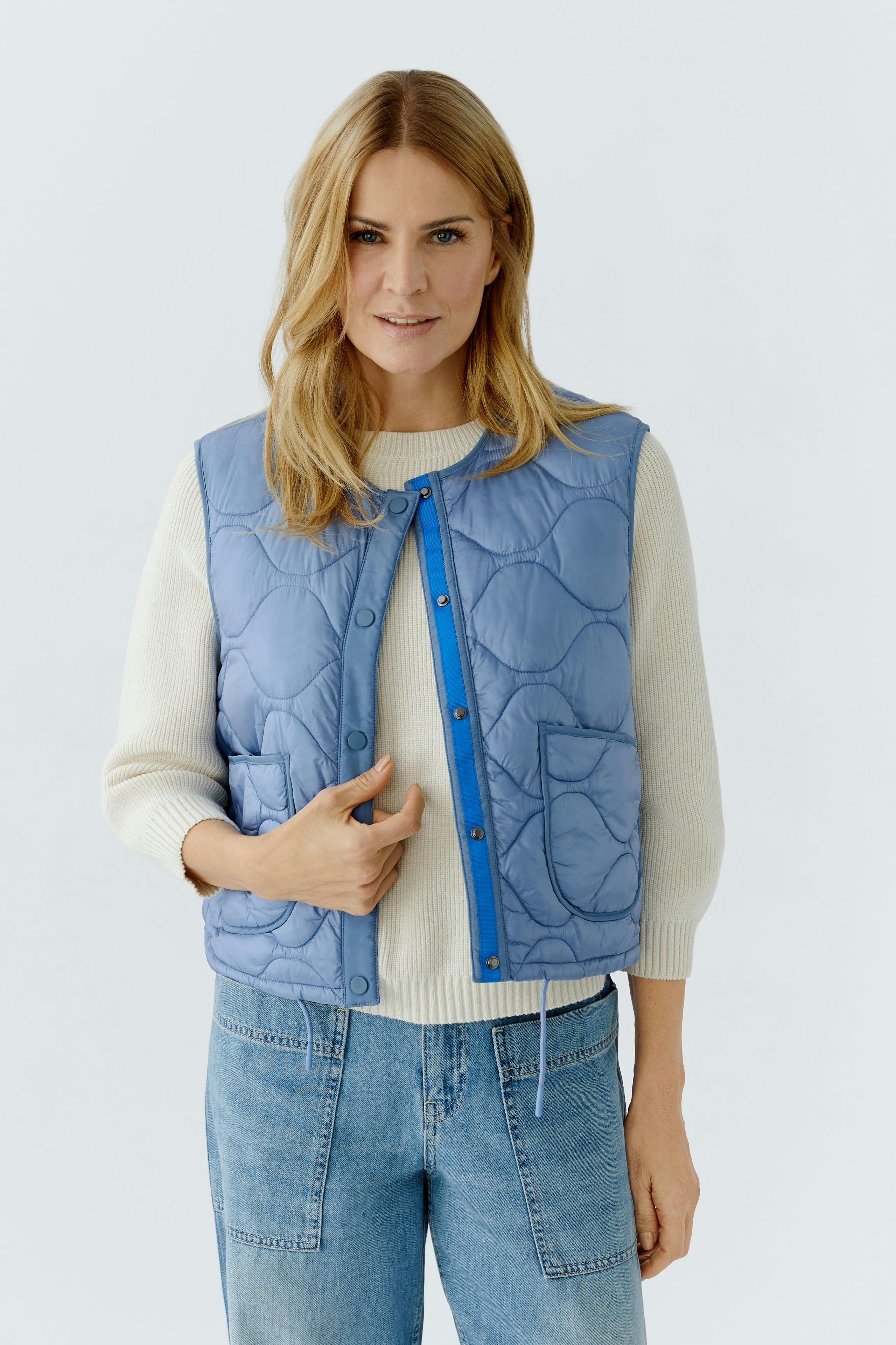 Reversible jacket: Woman in a light blue quilted jacket with a casual style, featuring a snap closure.