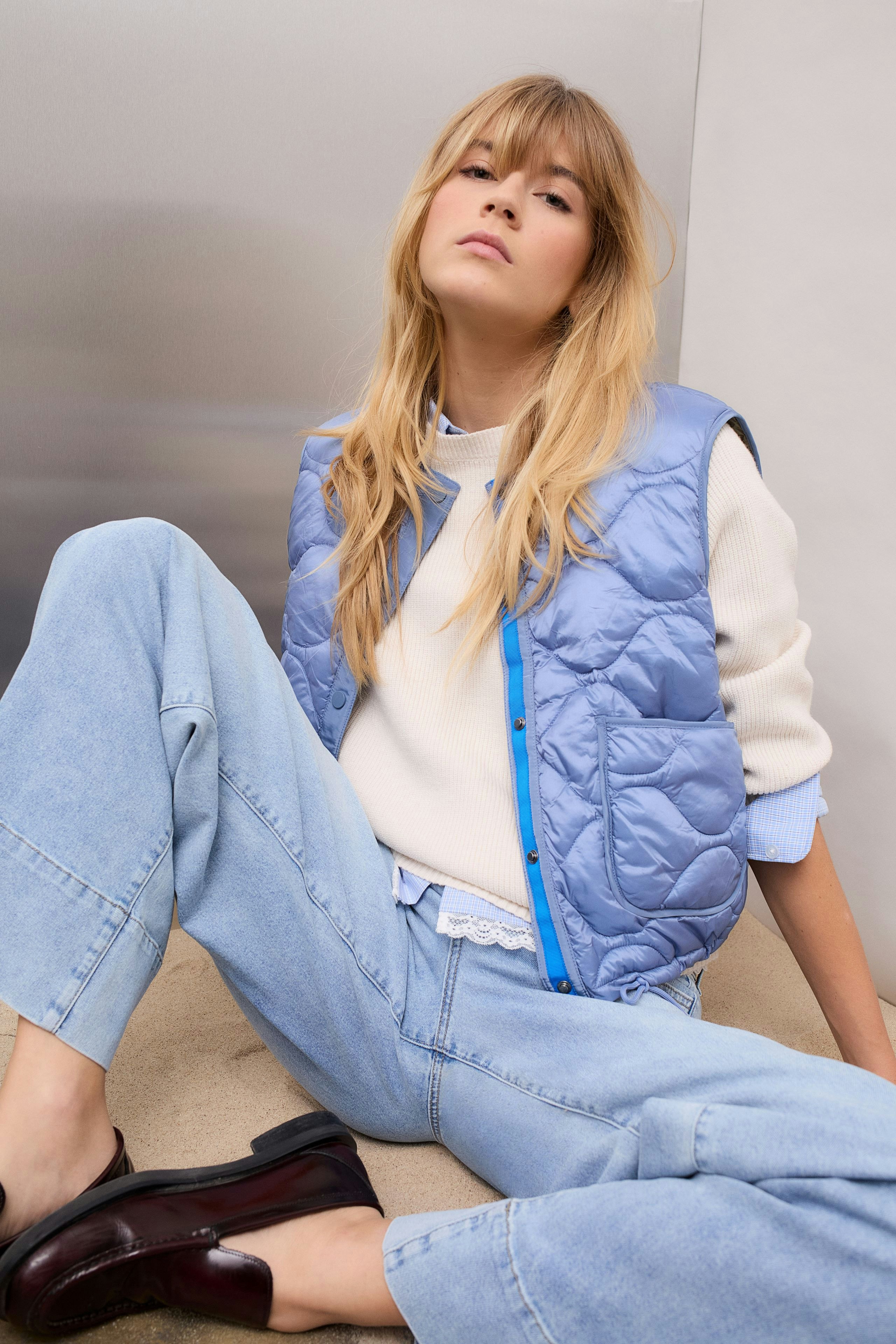 Reversible jacket: Young woman in a light blue quilted jacket over a white pullover and relaxed jeans.