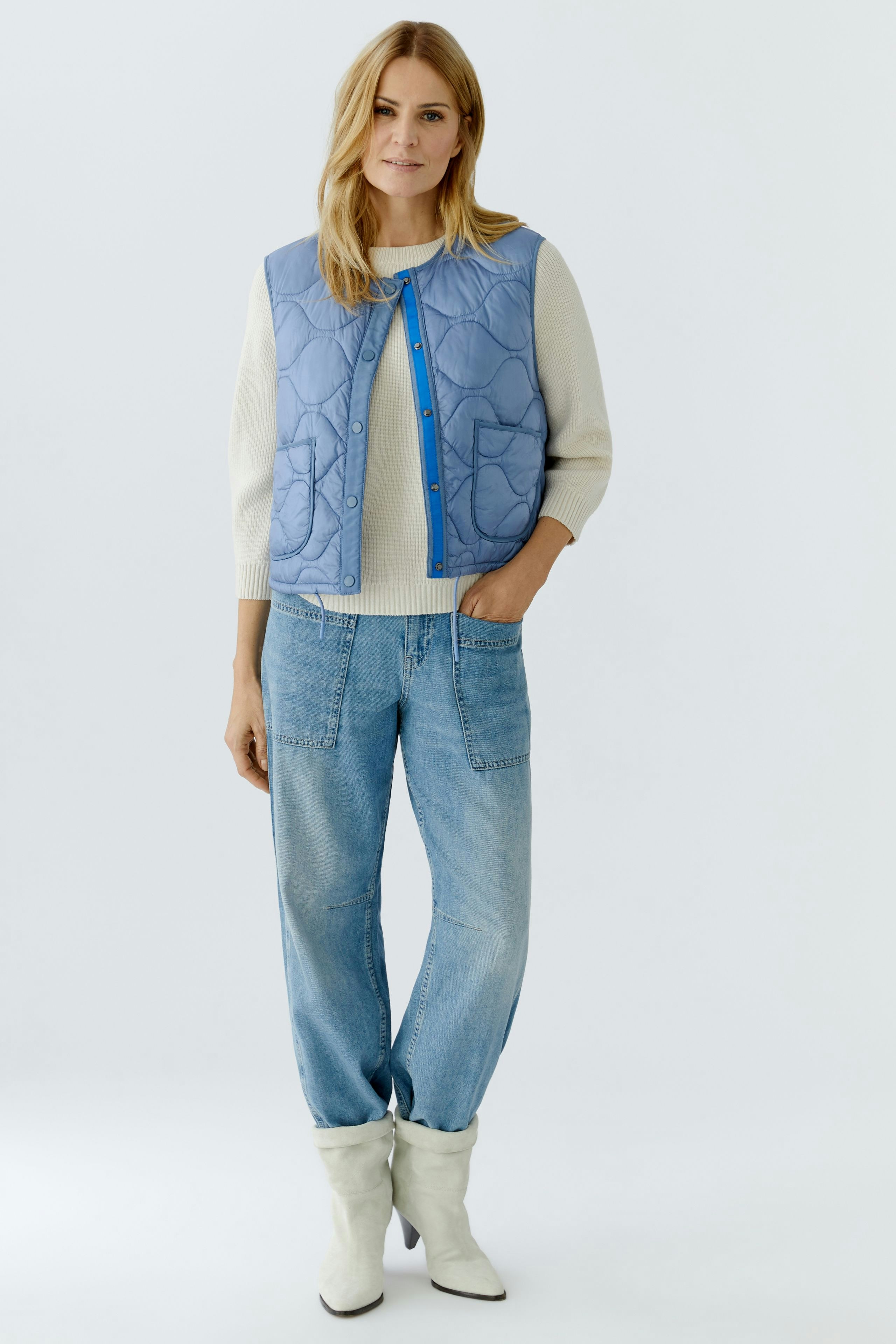 Reversible jacket: Woman in a light blue quilted jacket over a cream pullover and relaxed jeans.
