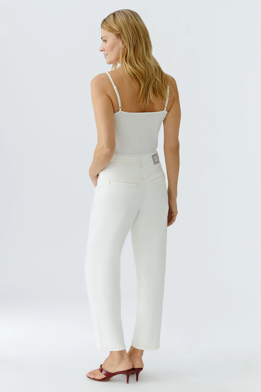 Relaxed fit women's jeans: A woman in white relaxed jeans and a simple top, showcasing a casual style.