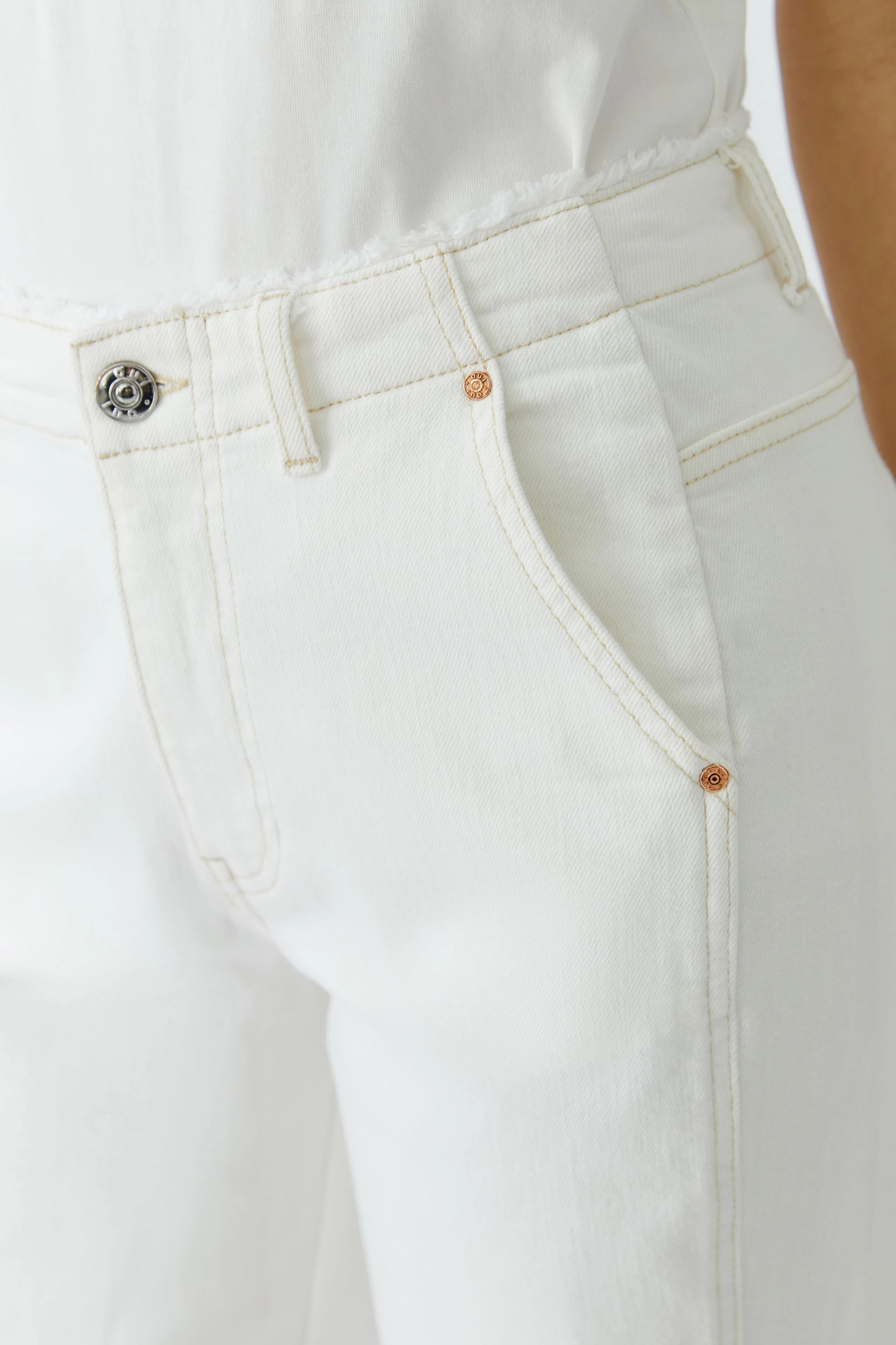 Bequeme Damen-Jeans: Frau trägt entspannte, weiße Jeans mit lässigem Schnitt und praktischen Taschen.