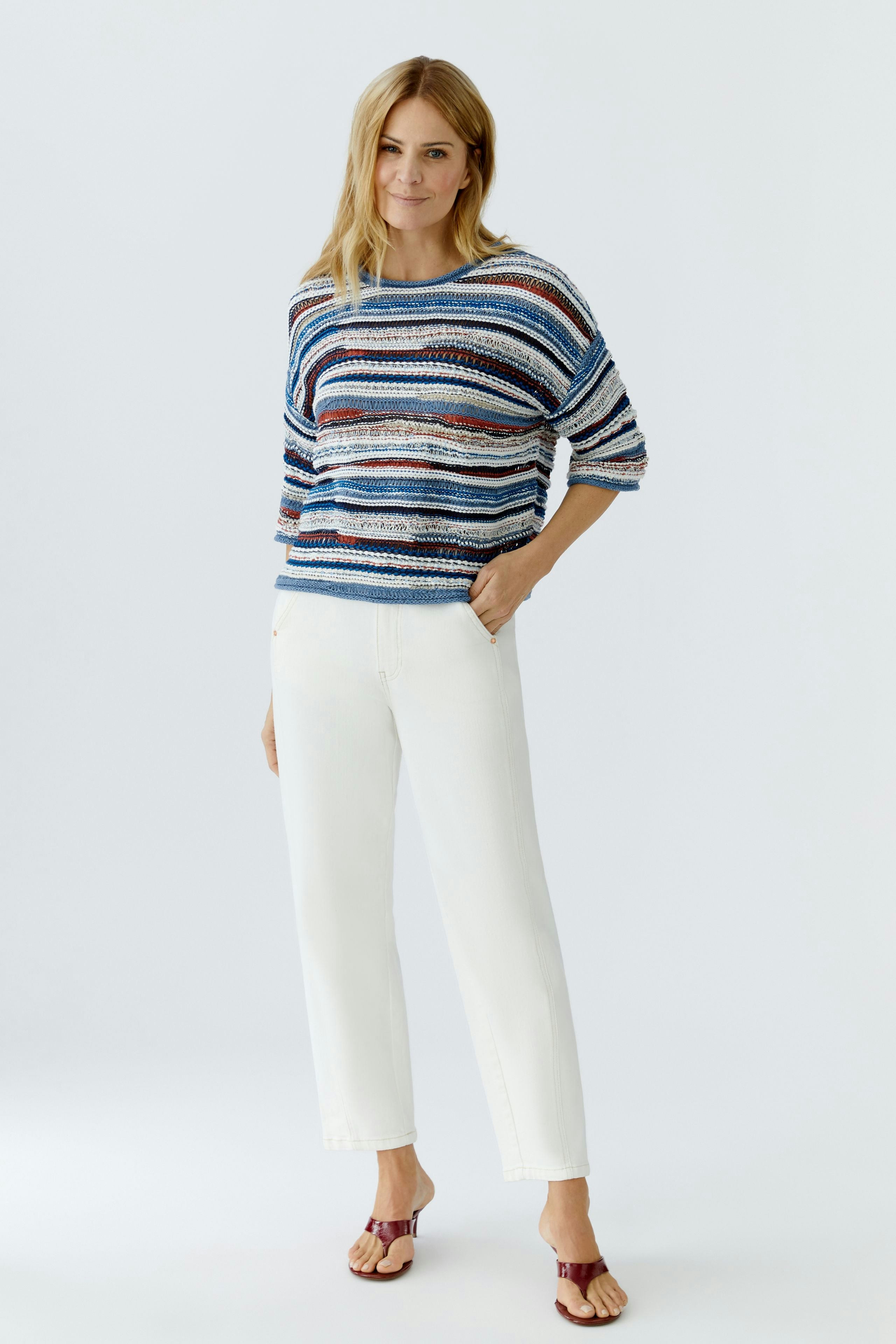 Casual women's relaxed jeans: A woman in stylish relaxed-fit jeans paired with a colorful striped pullover.