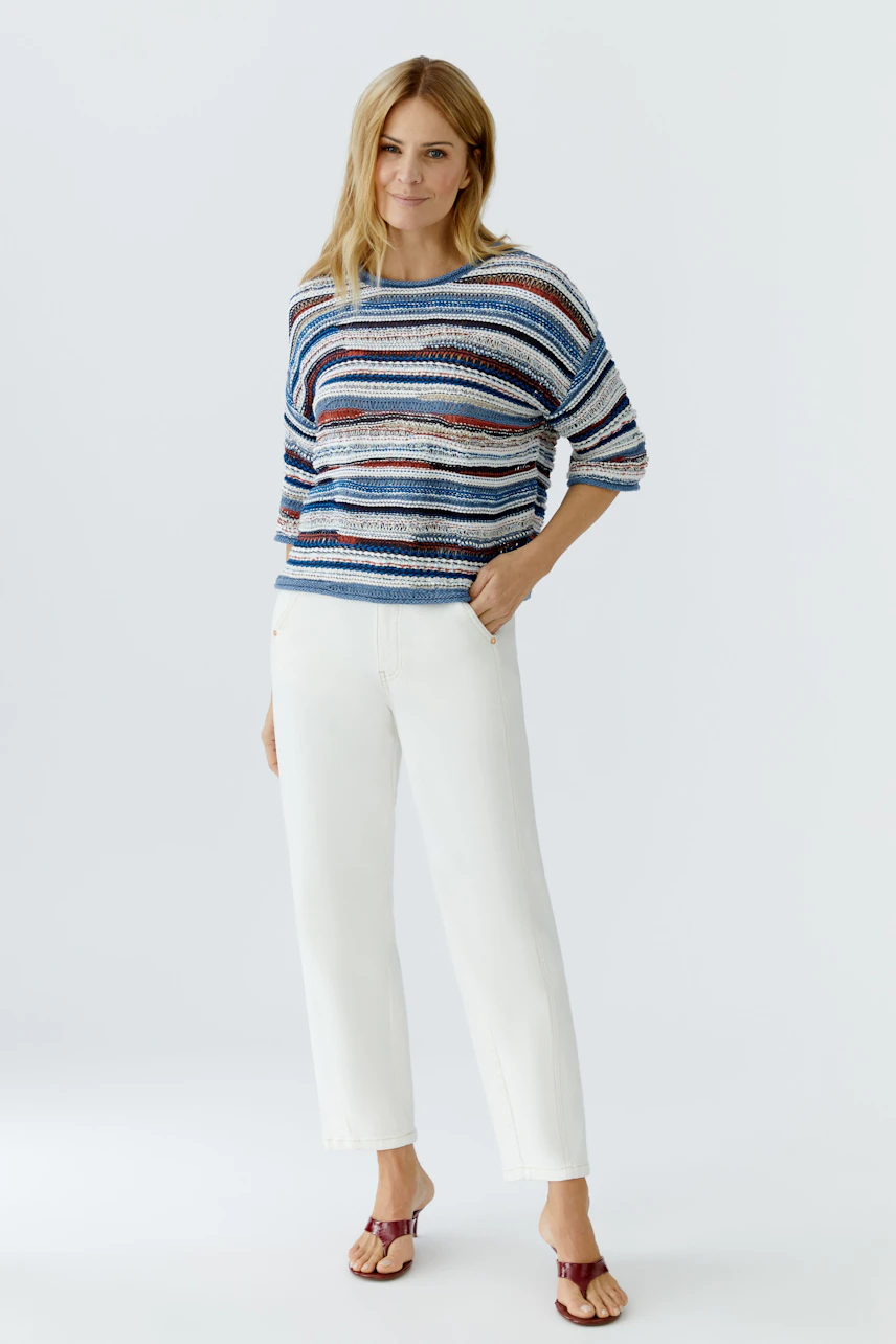 Casual women's relaxed jeans: A woman in stylish relaxed-fit jeans paired with a colorful striped pullover.