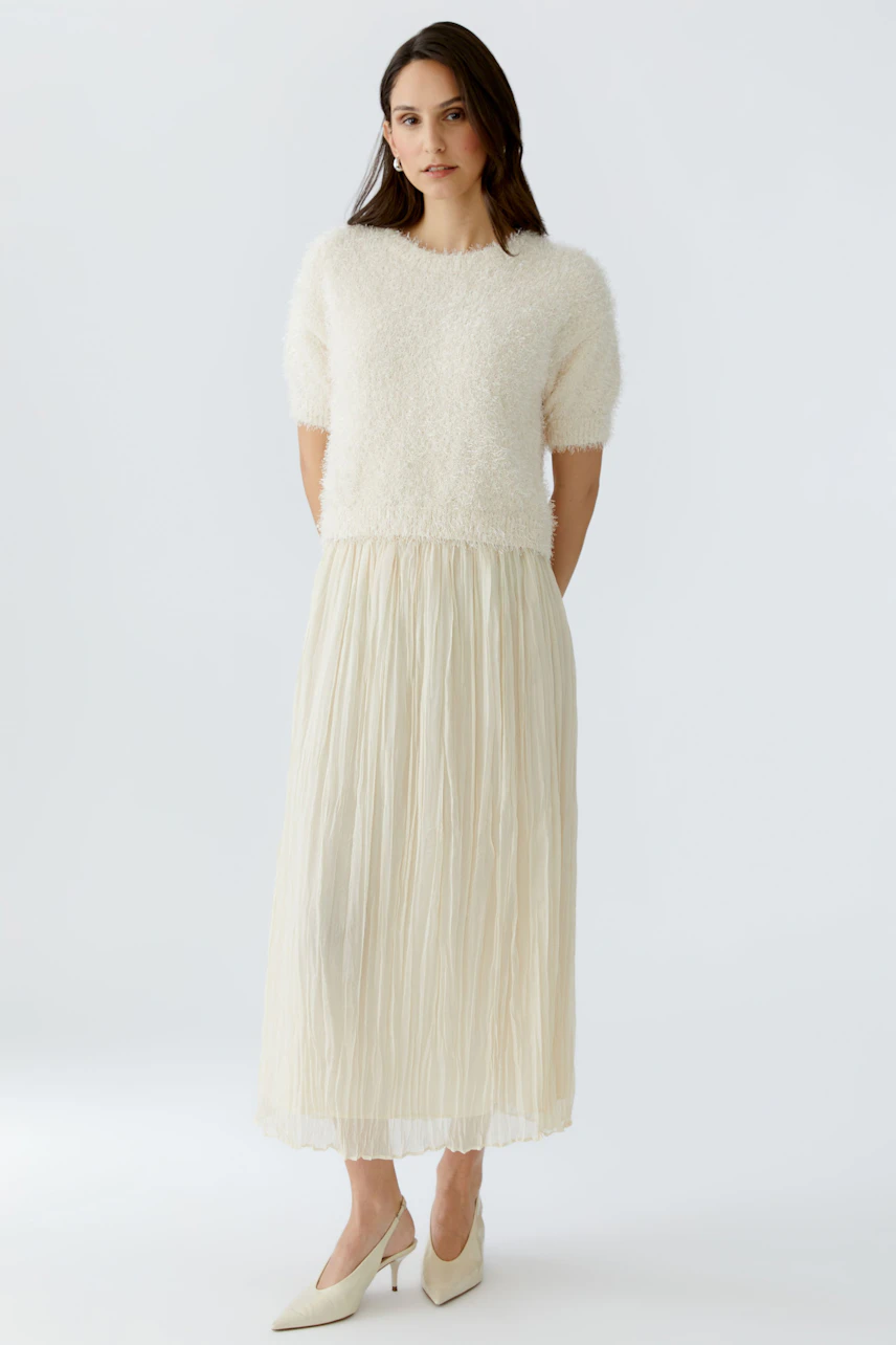 Lightweight pleated skirt: Woman in a soft, cream-colored pleated skirt paired with a fluffy pullover.