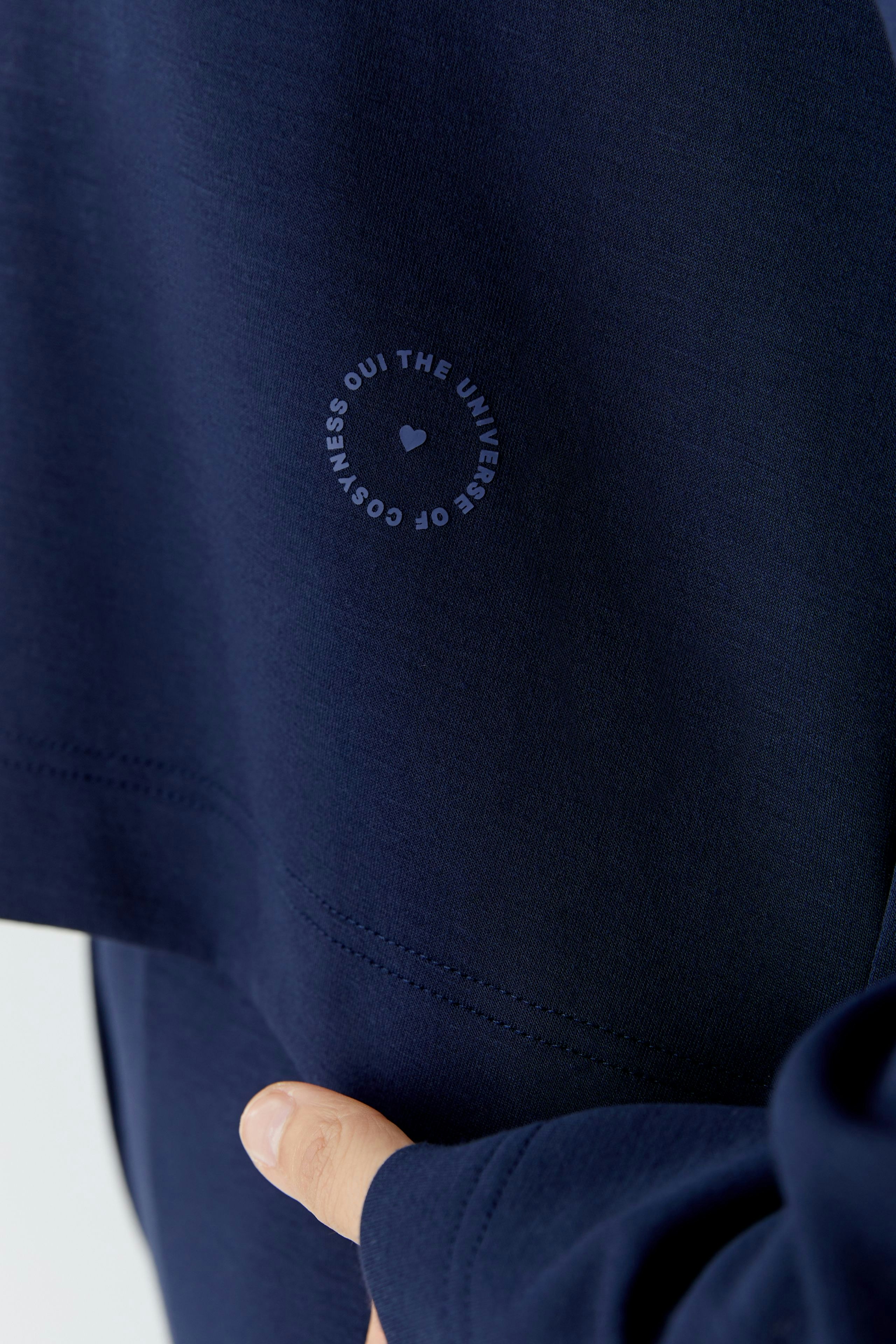 Casual women's hoodie: Close-up of a woman wearing a navy pullover with a logo detail.