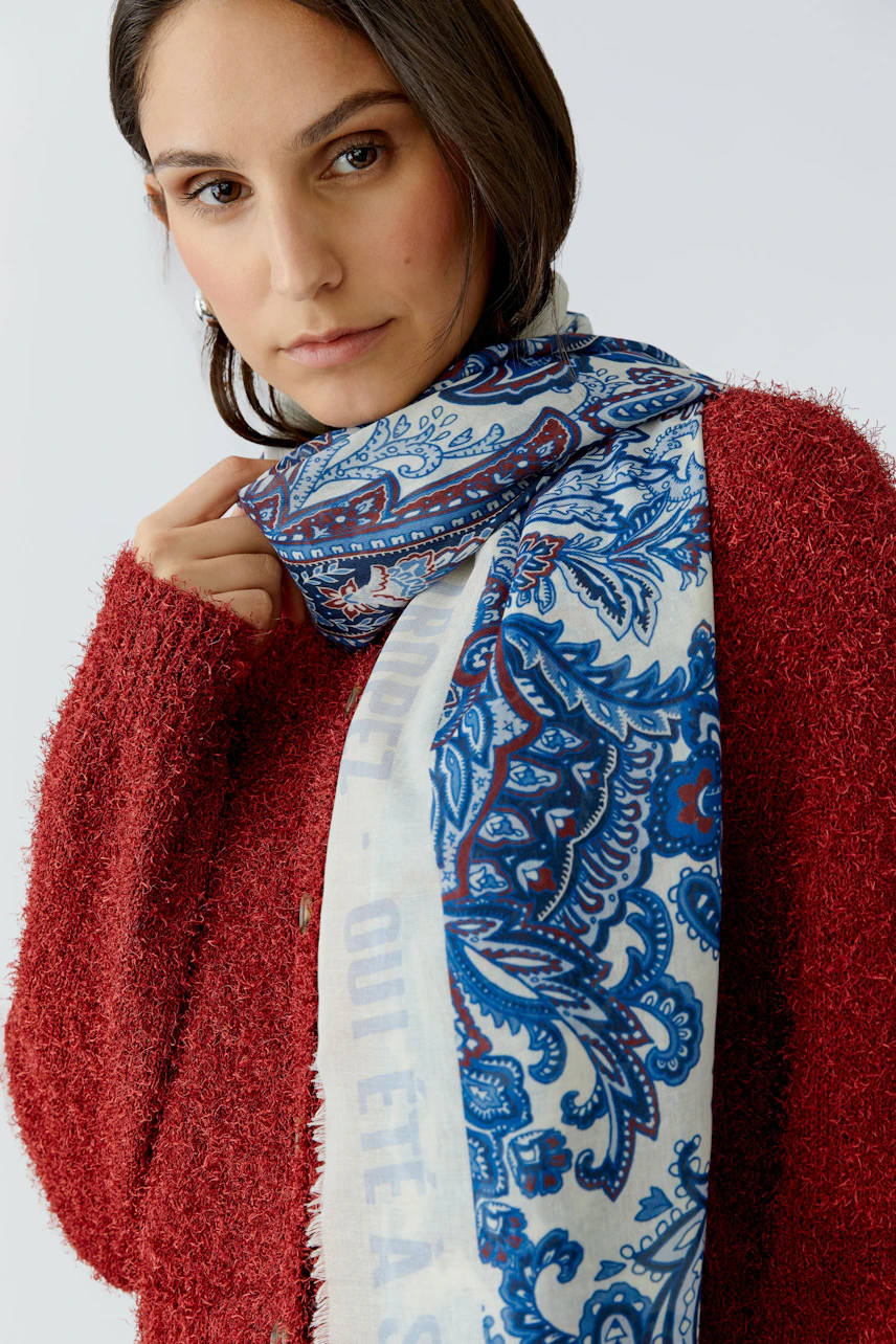Damen-Schal: Frau trägt einen bunten Schal mit Paisleymuster, kombiniert mit einem roten Pullover.