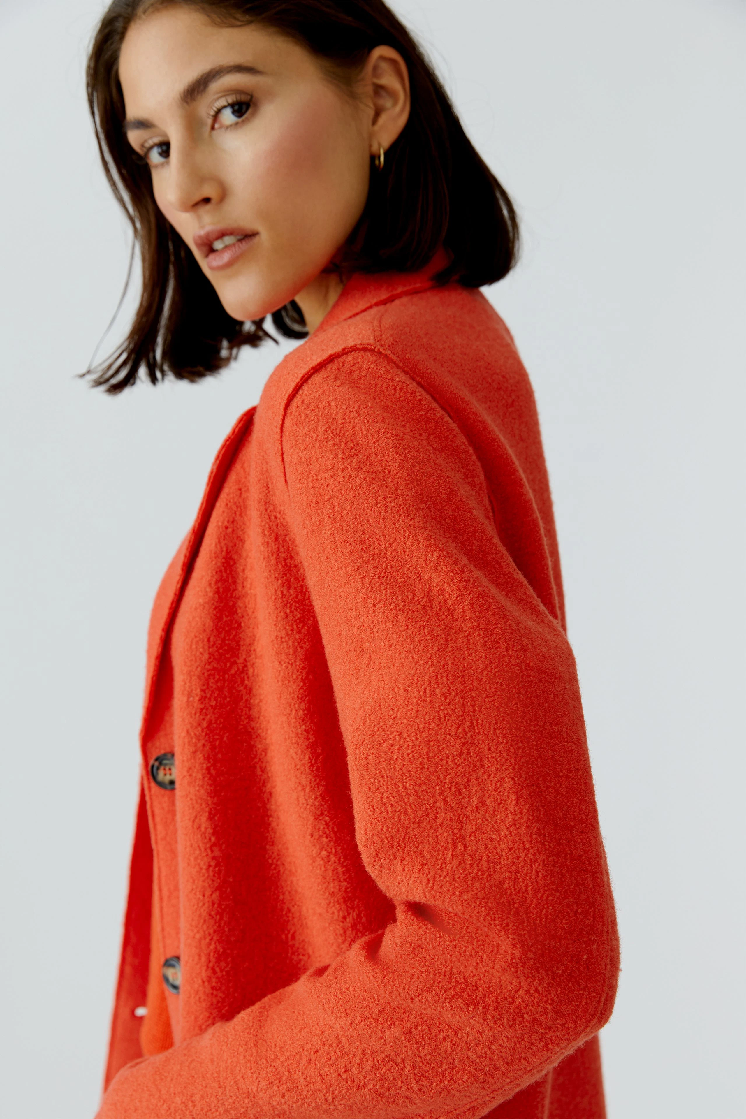 Damen Wollmantel: Frau in einem orangefarbenen, weichen Wollmantel mit Knöpfen, lässiger Look.