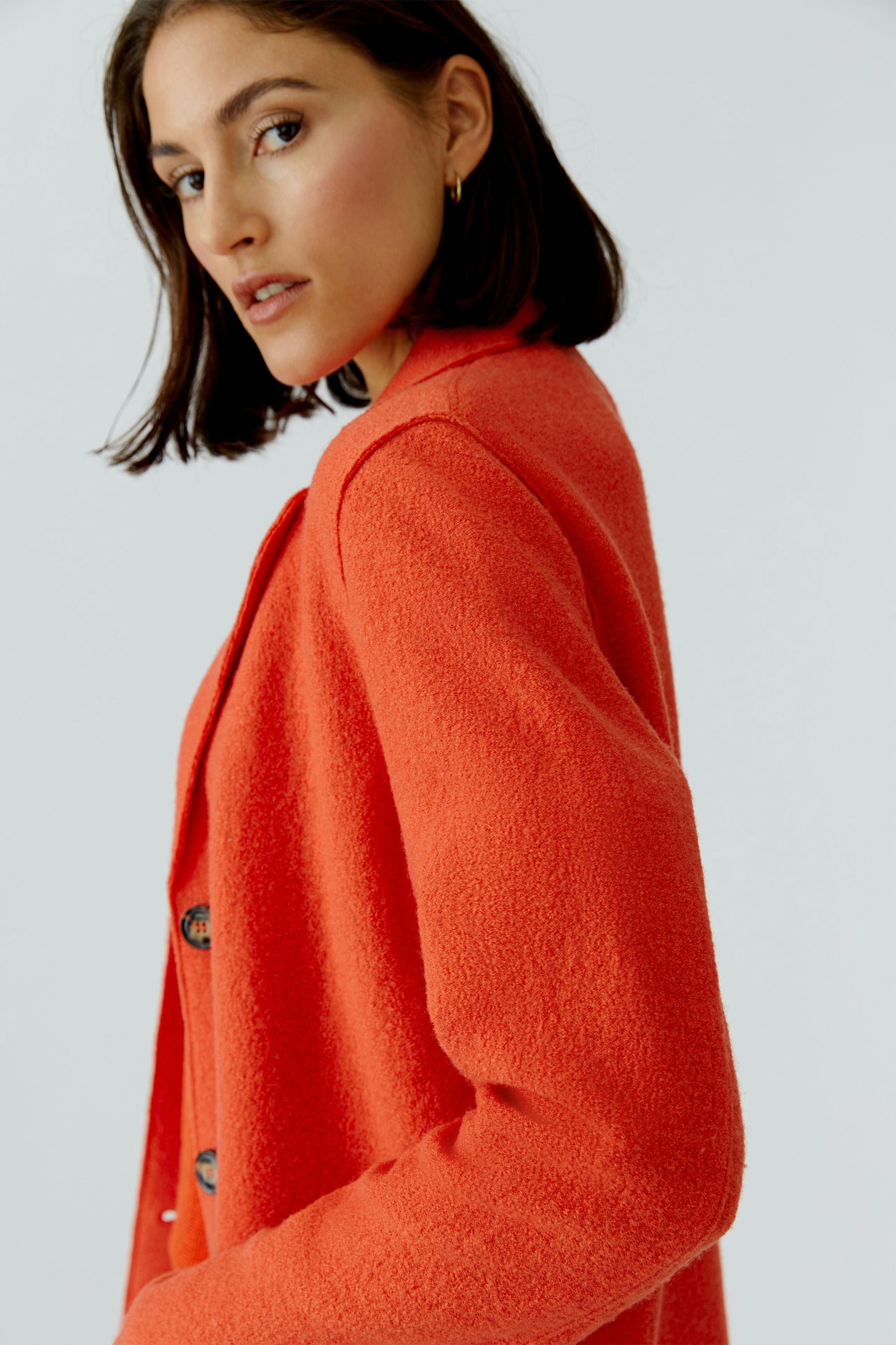 Damen Wollmantel: Frau in einem orangefarbenen, weichen Wollmantel mit Knöpfen, lässiger Look.